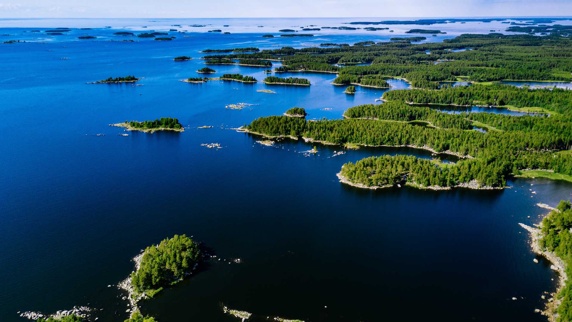 Luchtfoto van levendige blauwe meren en weelderige groene bossen in het landelijke Åland op een zonnige zomerdag.