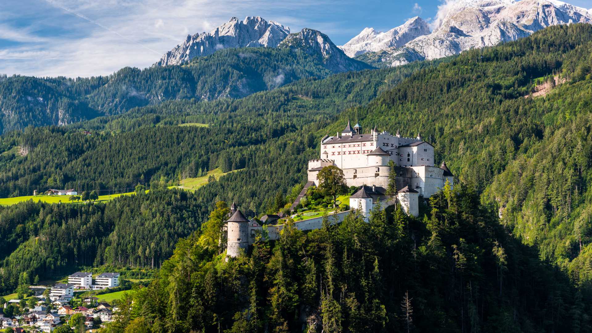 Kasteel Hohenwerfen op een heuveltop, omlijst door weelderige bossen en de Oostenrijkse Alpen.