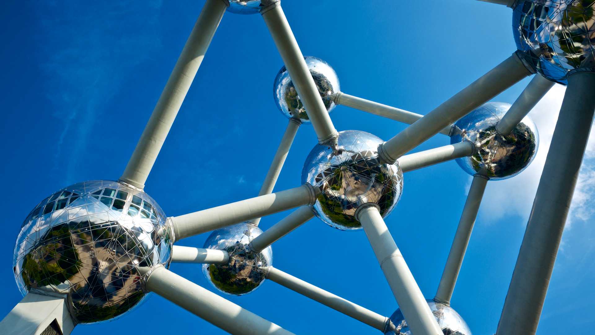 A low-angle view of the Atomium in Brussels, its gleaming spheres stand out against the clear blue sky.