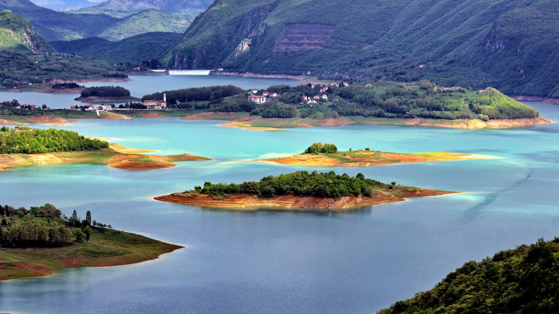 Weelderige eilanden onderbreken het turquoise water van Lake Varvara, omgeven door groene heuvels in Bosnië en Herzegovina.