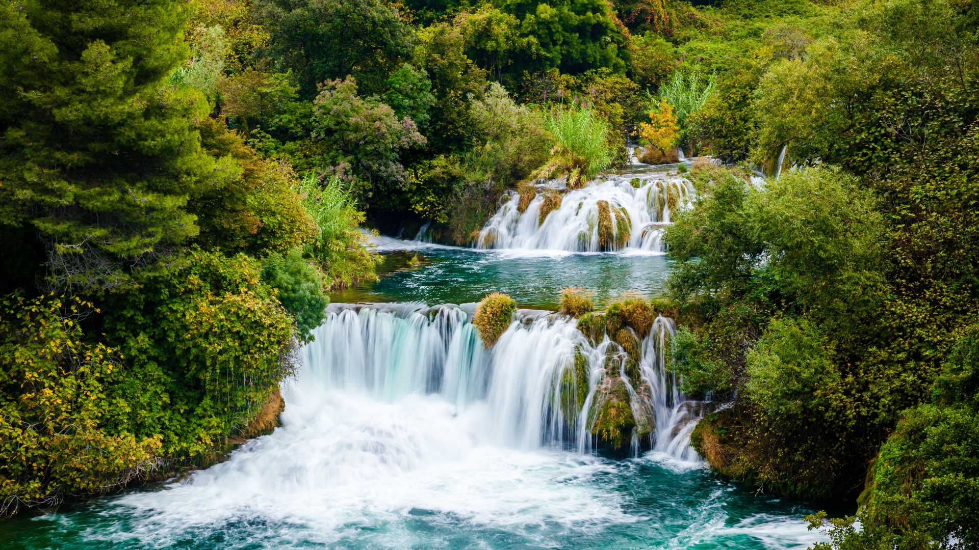Cascading waterfalls surrounded by lush greenery in Krka National Park, Croatia.