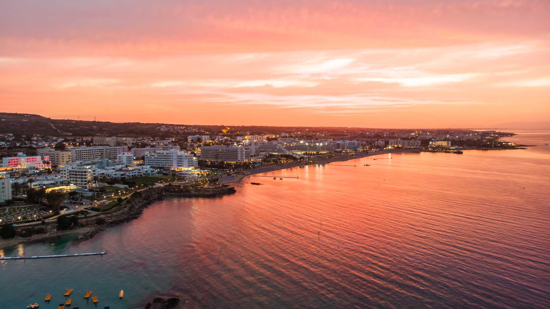 Sunset over Protaras, Cyprus, casting warm hues across the city and sea.