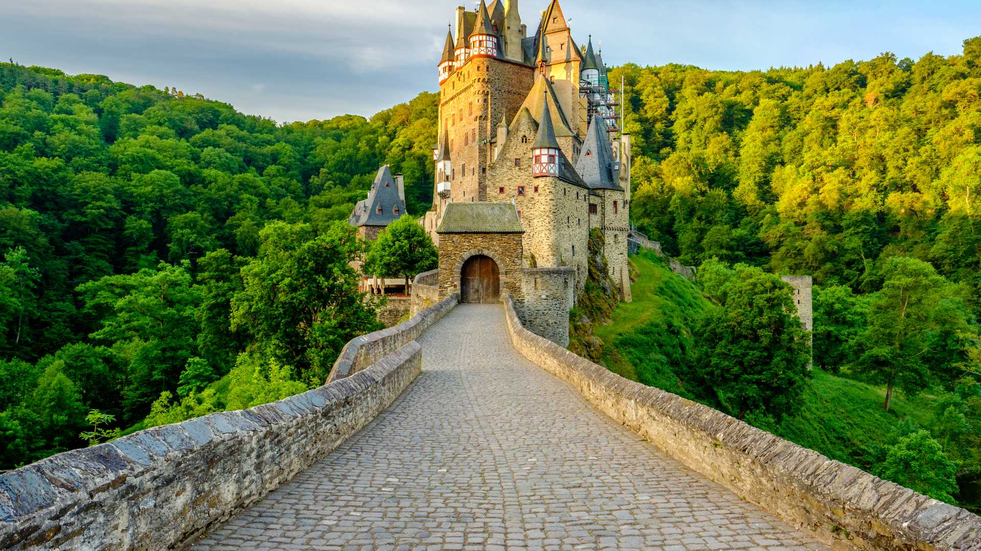 Eltz Castle, a medieval fortress, stands proudly amidst a vibrant green forest.
