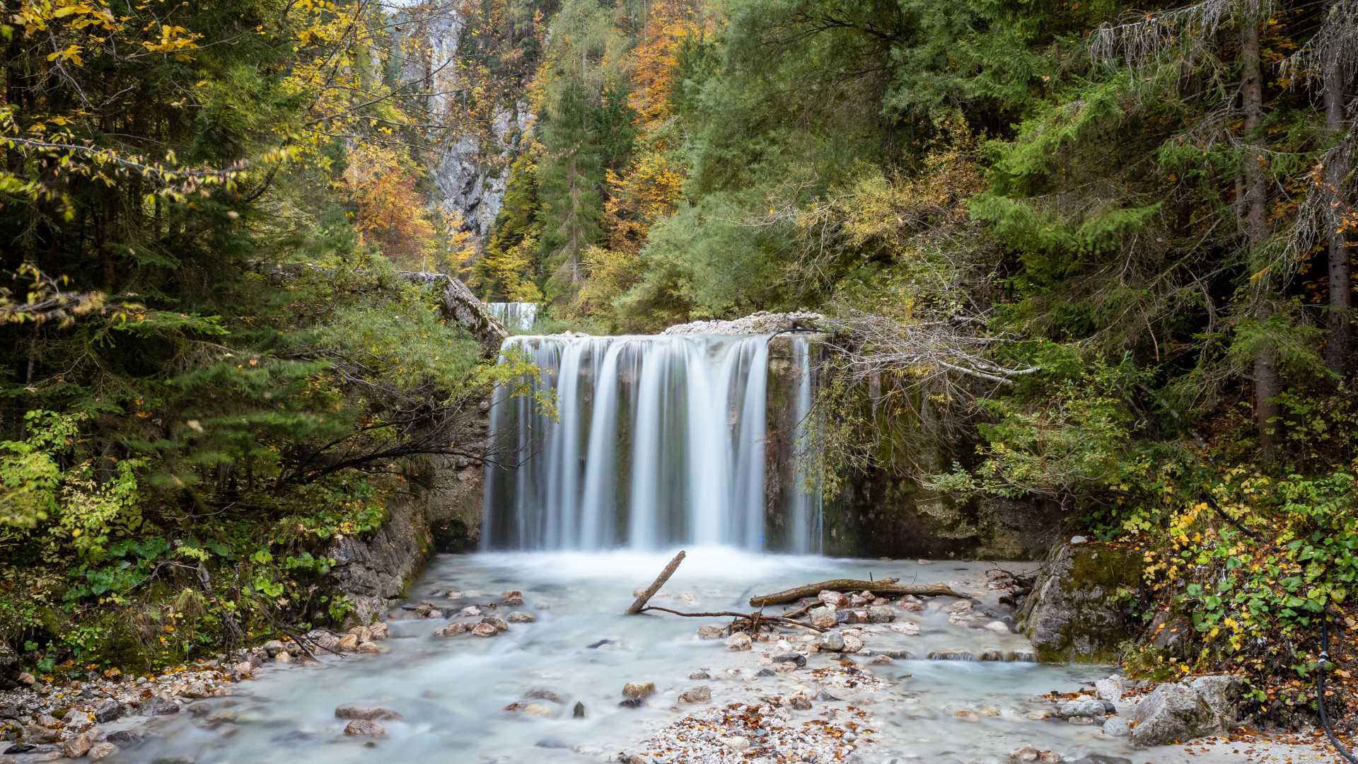 Der untere Martuljek-Wasserfall inmitten üppigen Herbstlaubes in den Julischen Alpen, Slowenien.