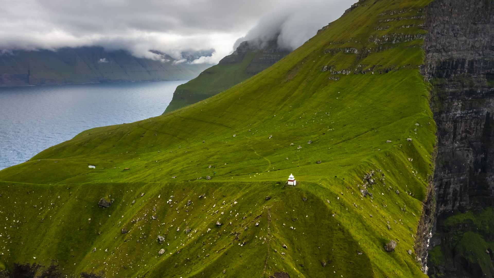 Aerial view of Kallur Lighthouse on the green cliffs of Kalsoy Island, Faroe Islands.