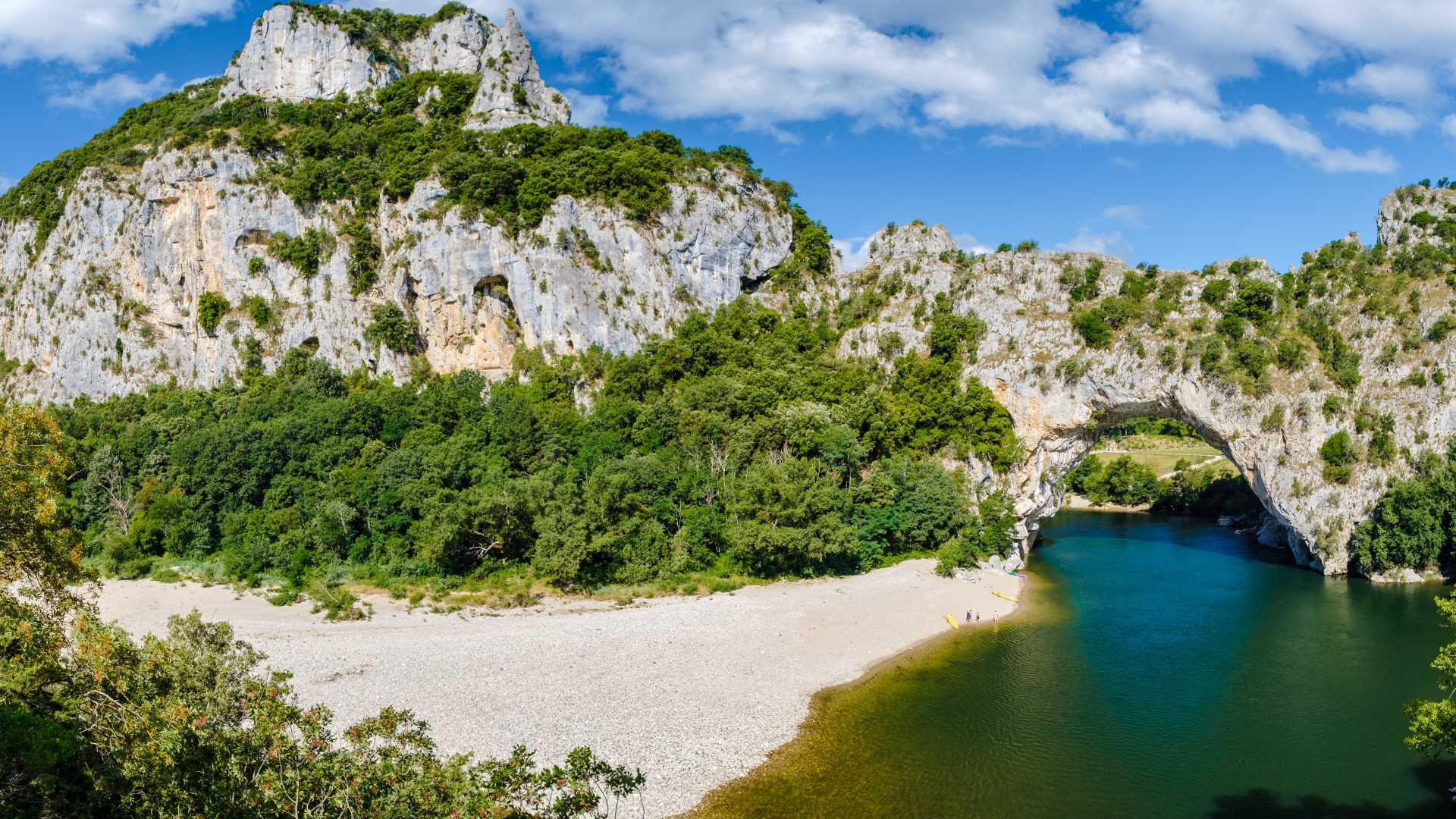 Arco naturale Pont d'Arc in Ardèche, Francia, con vegetazione lussureggiante e il fiume Ardèche che scorre sotto.