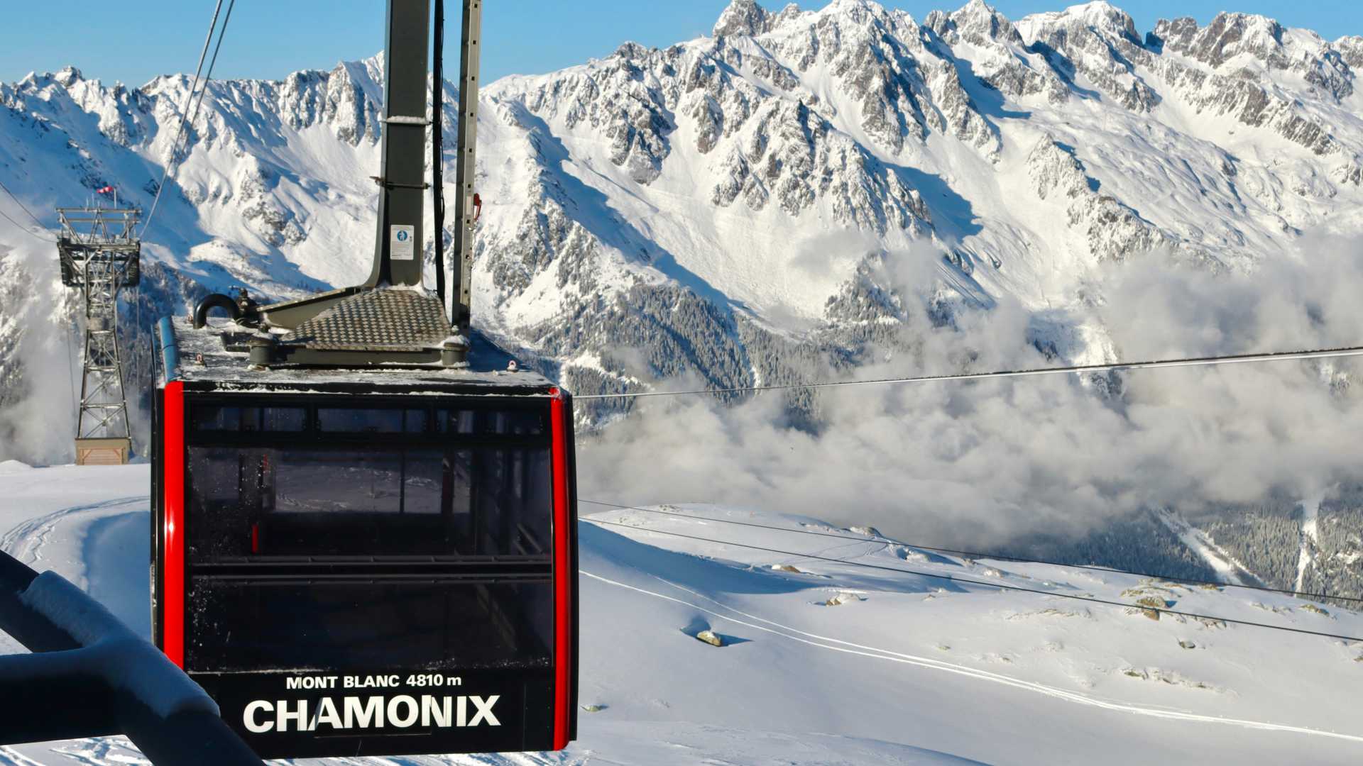 Un téléski monte vers le Mont Blanc à Chamonix, révélant des sommets déchiquetés et des paysages enneigés.