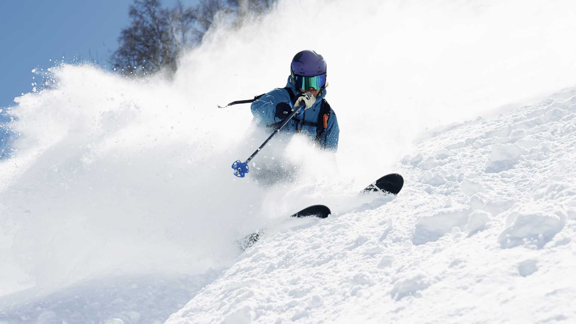 Een skiër snijdt door verse poeder op een zonnige dag in Alpe d'Huez, Rhône-Alpes, Frankrijk.