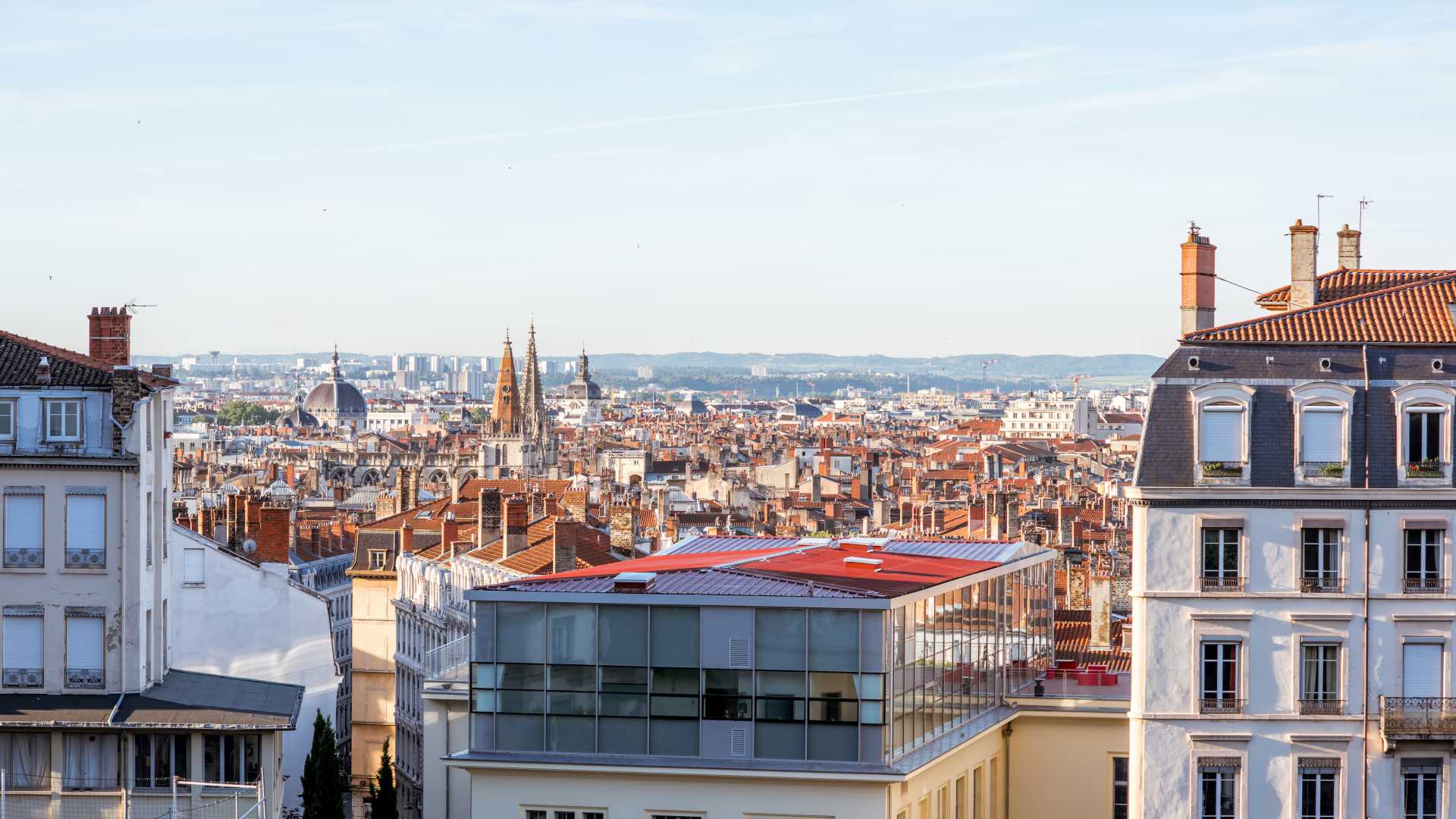 Charmant ochtendzicht op de daken van Lyon, historische gebouwen en verre torenspitsen onder een heldere hemel.