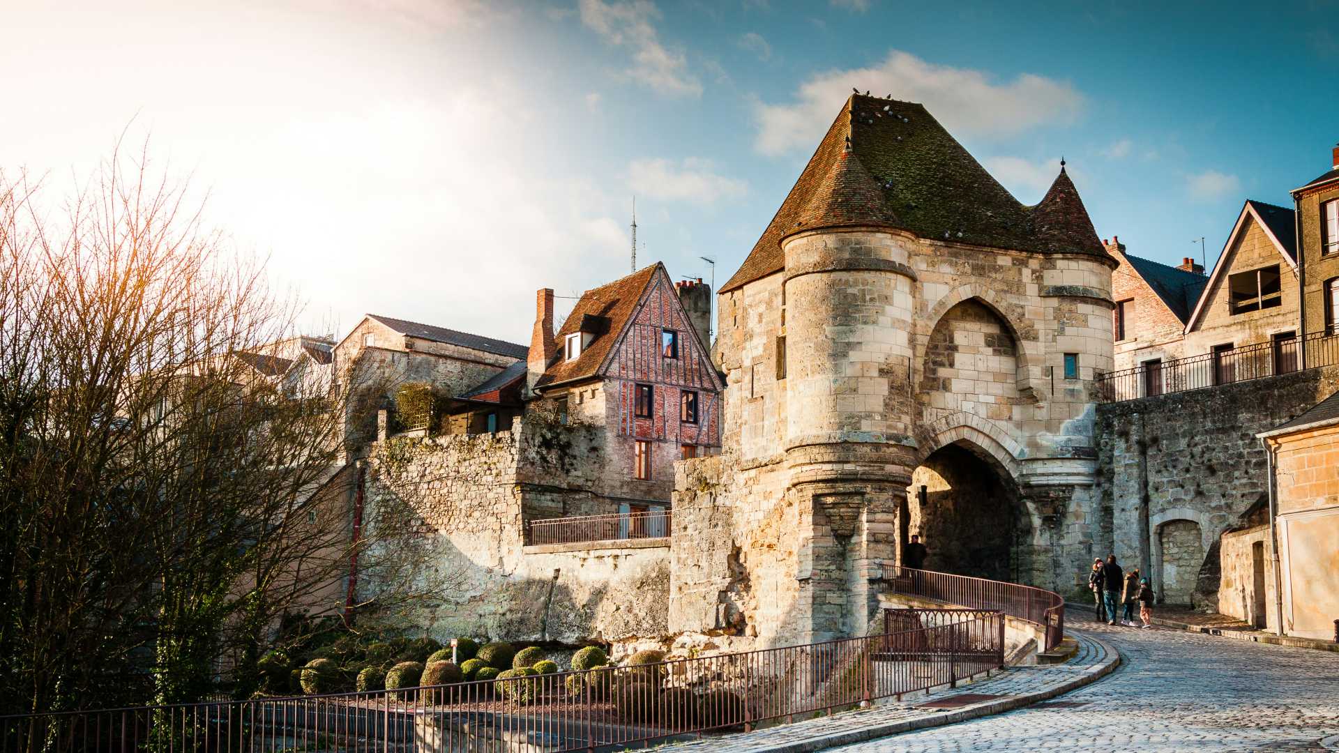 La Porte d’Ardon in Laon, a medieval gate with stone walls and turret, under a partly cloudy sky.