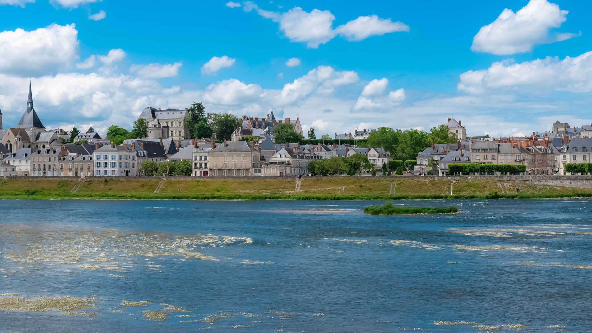 Panoramic view of Blois, France, featuring the Loire River and the historic Saint-Nicolas Church.