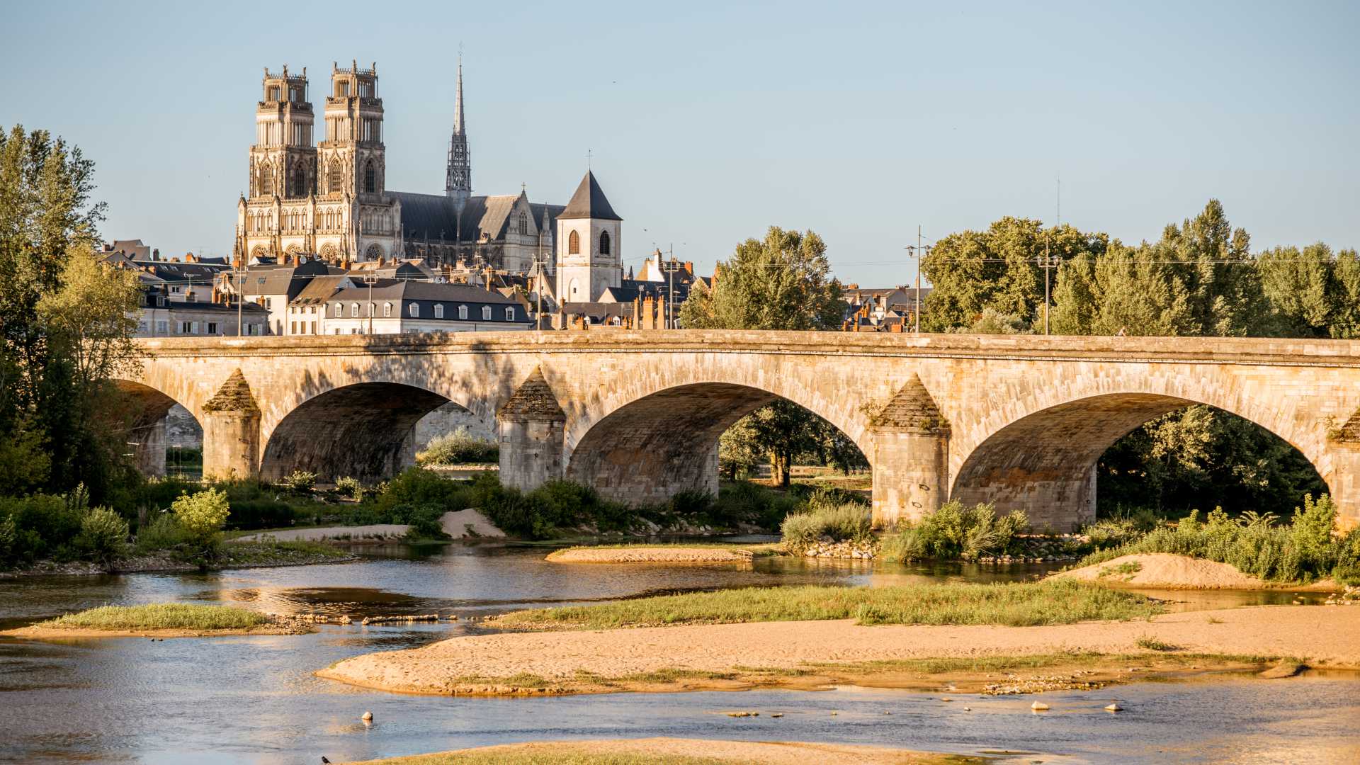 Historic stone bridge over the Loire River with the Orléans Cathedral in the background, Orléans, France.