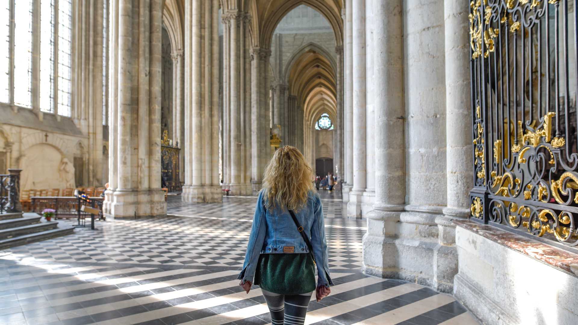 Un visitante camina por el magnífico interior de la Catedral de Amiens, admirando su impresionante arquitectura gótica y el juego de luces.
