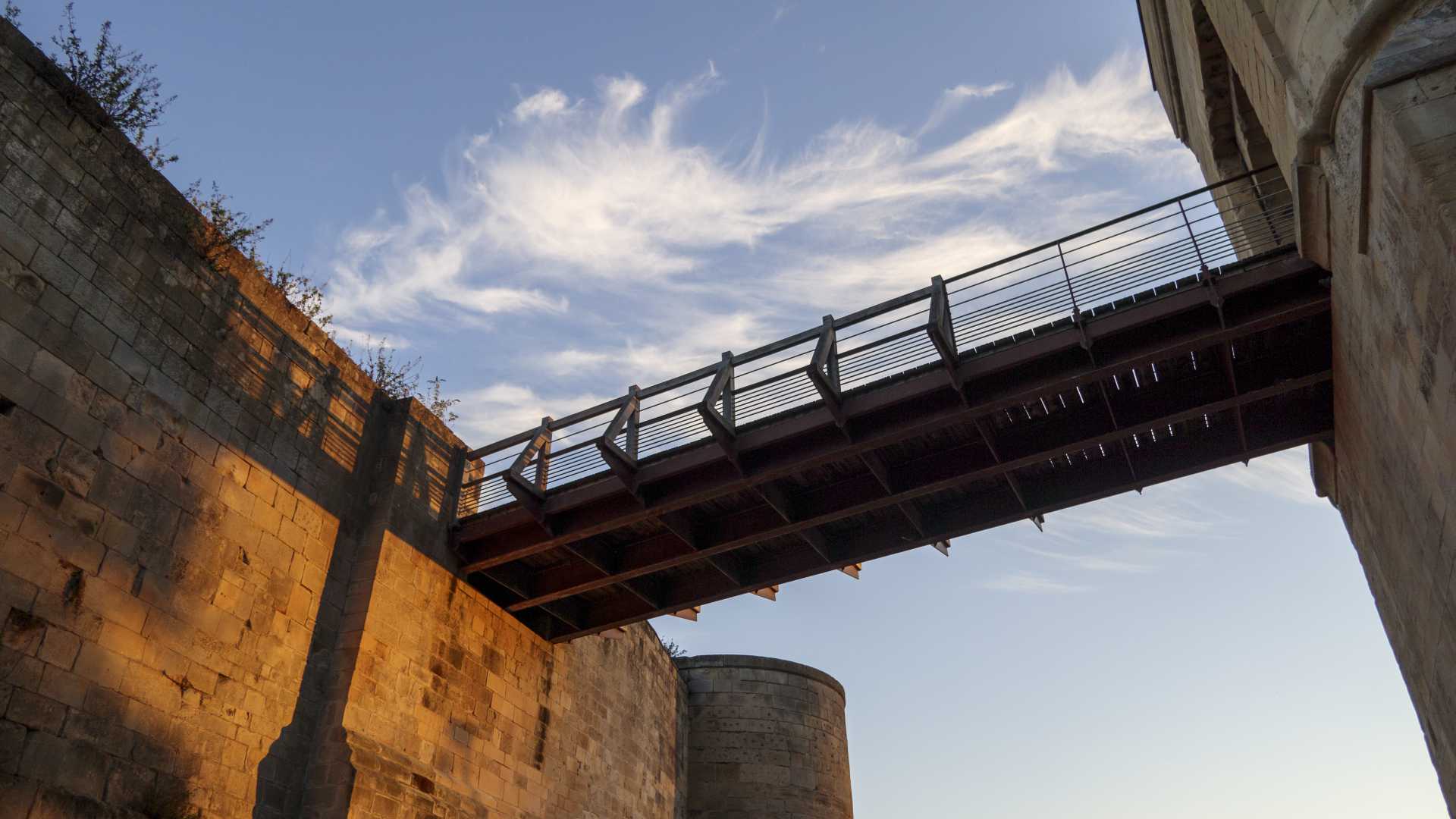 Stenen muren en een brug onder een hemel met dunne wolken in Caen, Normandië.