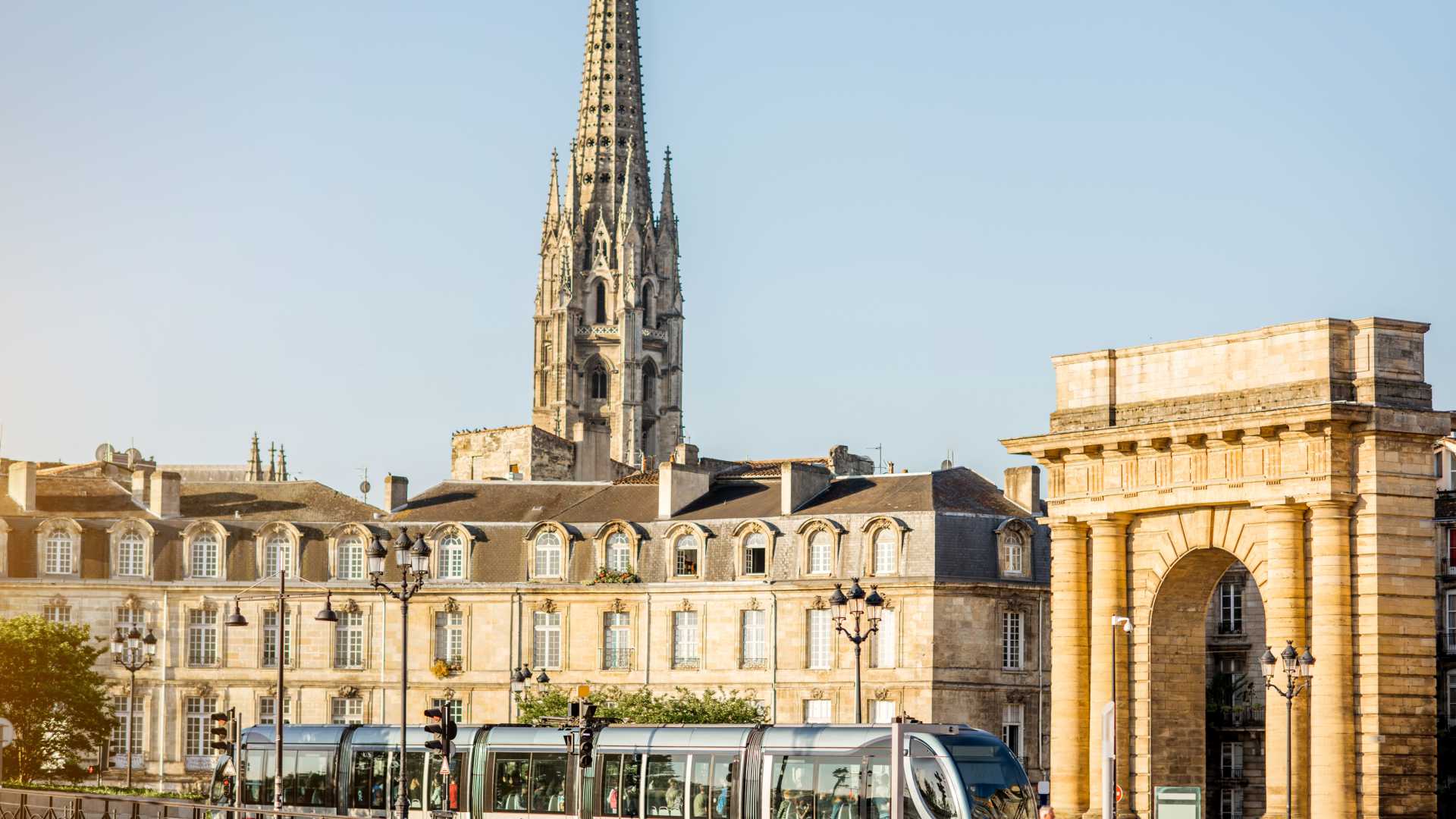 The Porte de Bourgogne and the spire of Saint-Michel Cathedral under the morning light in Bordeaux.