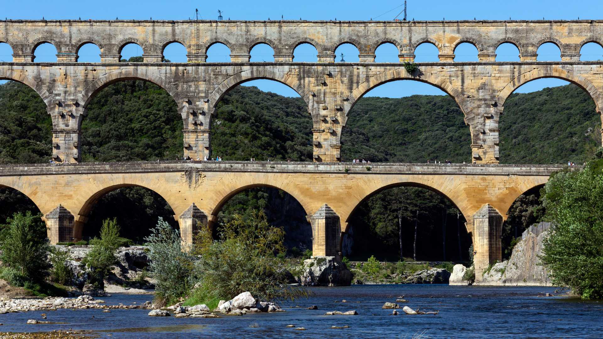 L'impressionnant Pont du Gard, un aqueduc romain, enjambe le Gardon au milieu d'un paysage verdoyant.