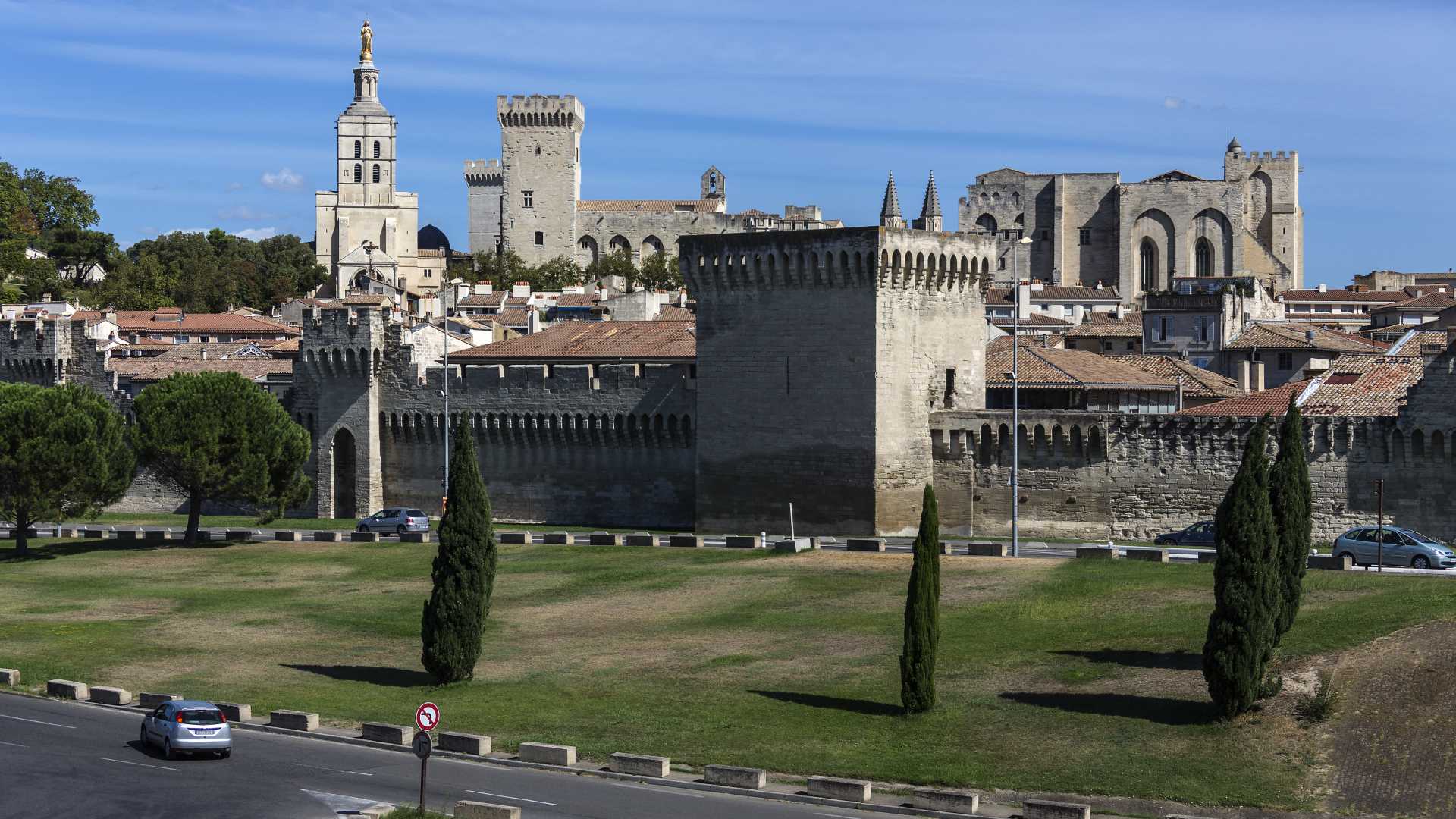 De skyline van Avignon, met zijn oude stadsmuren en het Palais des Papes onder een heldere blauwe lucht.