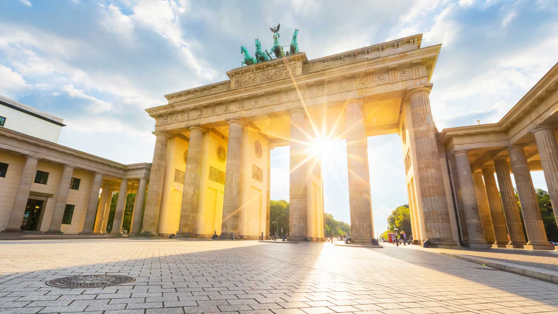 Sunlight streams through the Brandenburg Gate in Berlin, highlighting its majestic architecture.