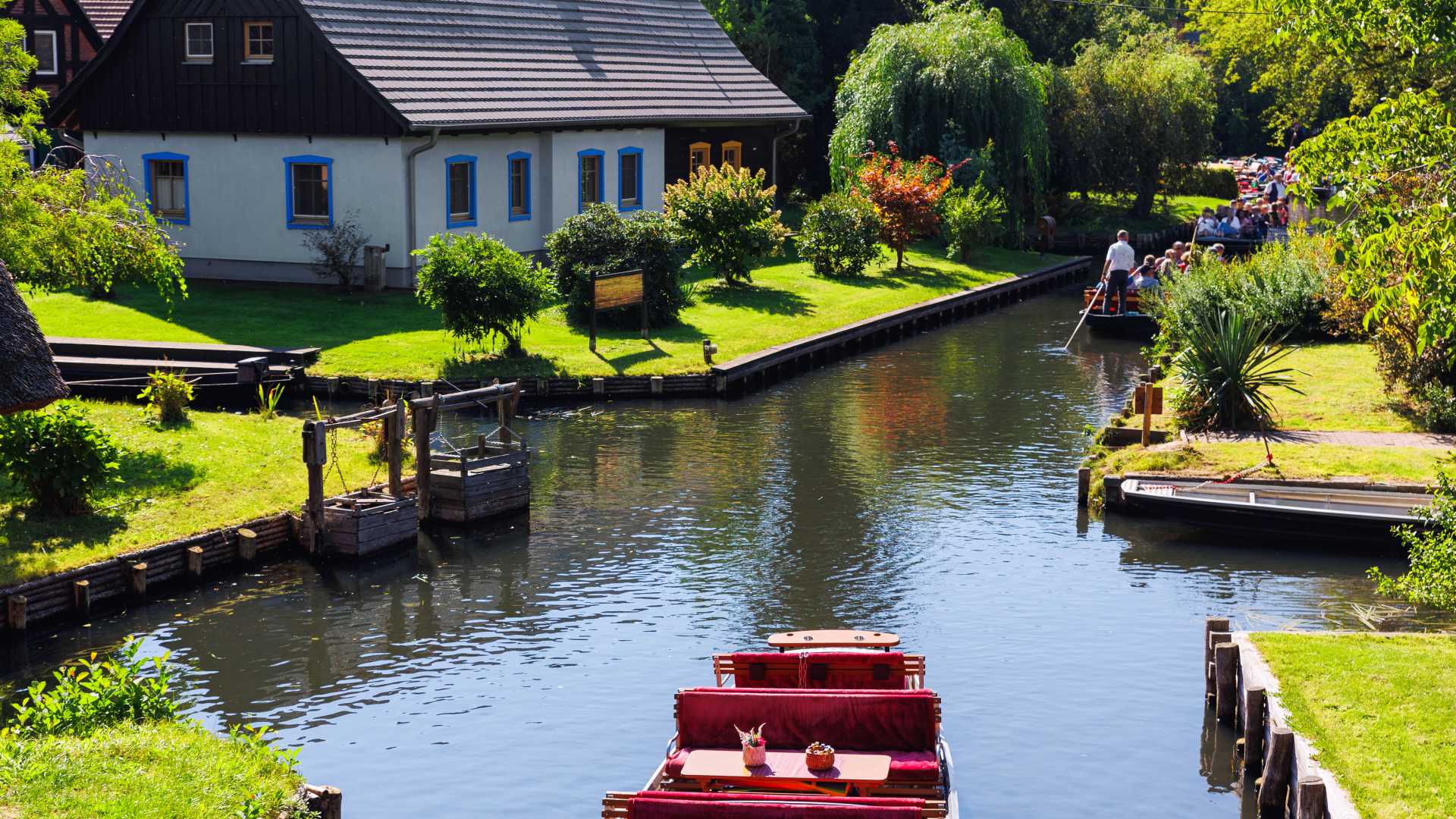 Charming riverside houses and canal boats in Spreewald, Germany, surrounded by lush greenery.