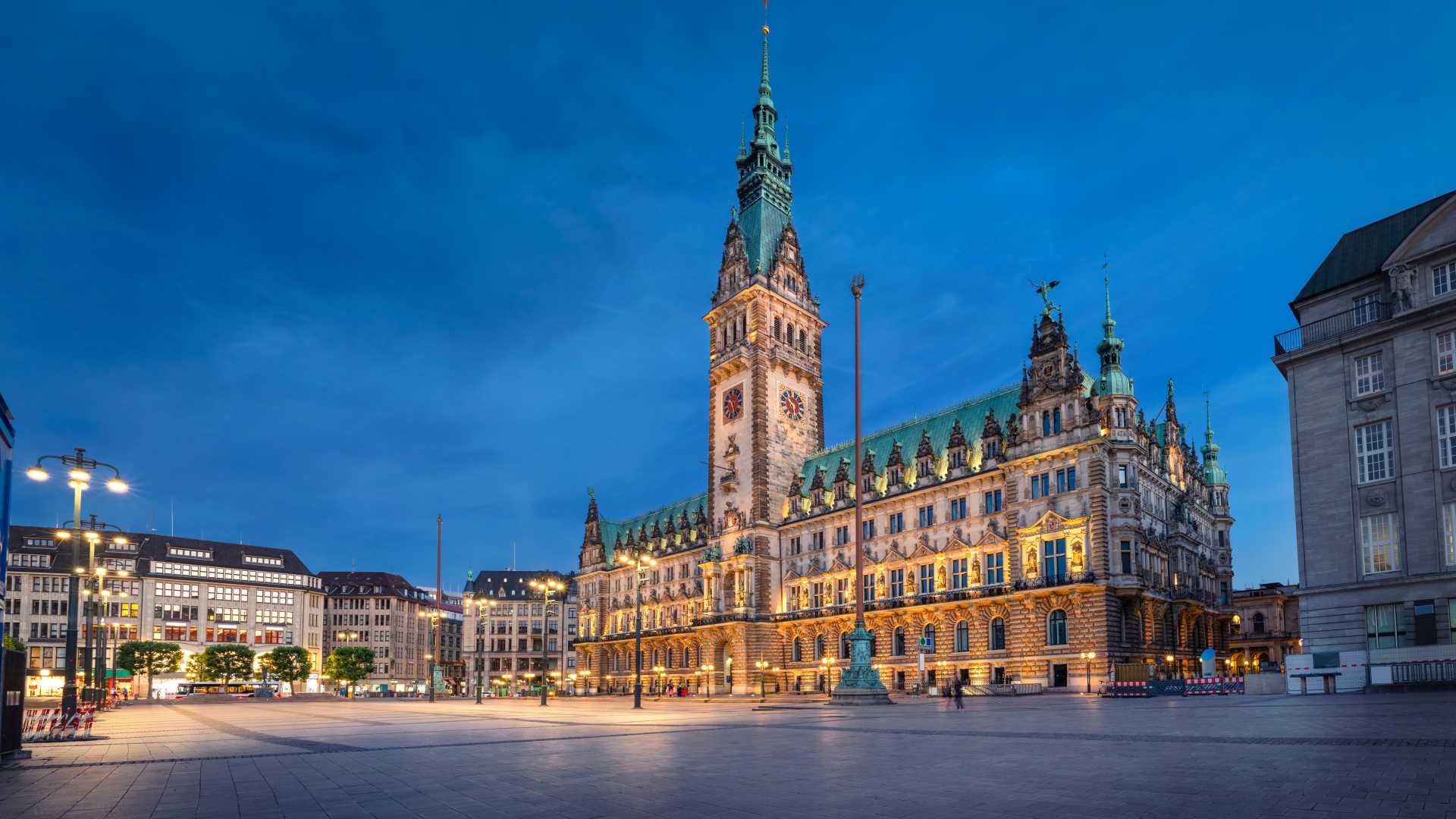 Illuminated Hamburg Town Hall at dusk, showcasing its grand architecture against a deep blue sky.