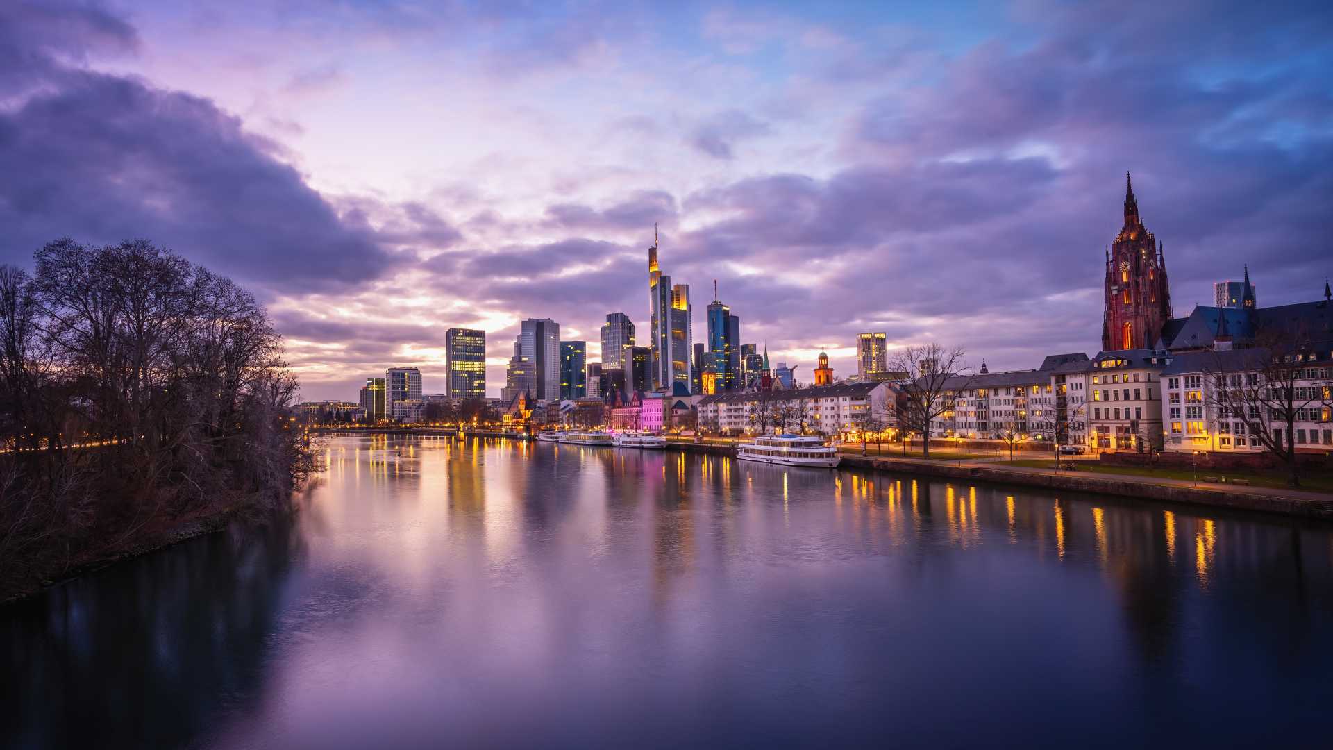 Frankfurt skyline at dusk, reflecting purple hues on the Main River.