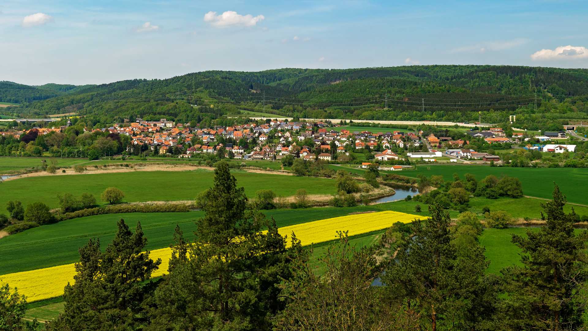 Herleshausen village surrounded by green fields and forests, viewed from Brandenburg Castle.