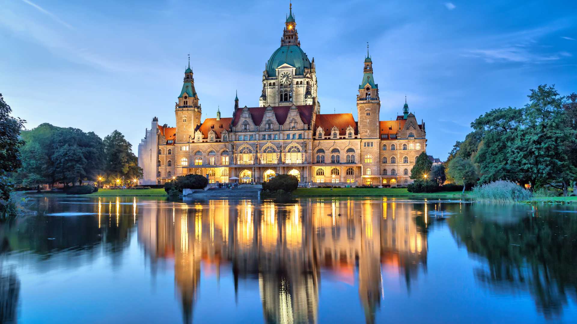 Hannover City Hall illuminated at dusk reflecting in a pond.