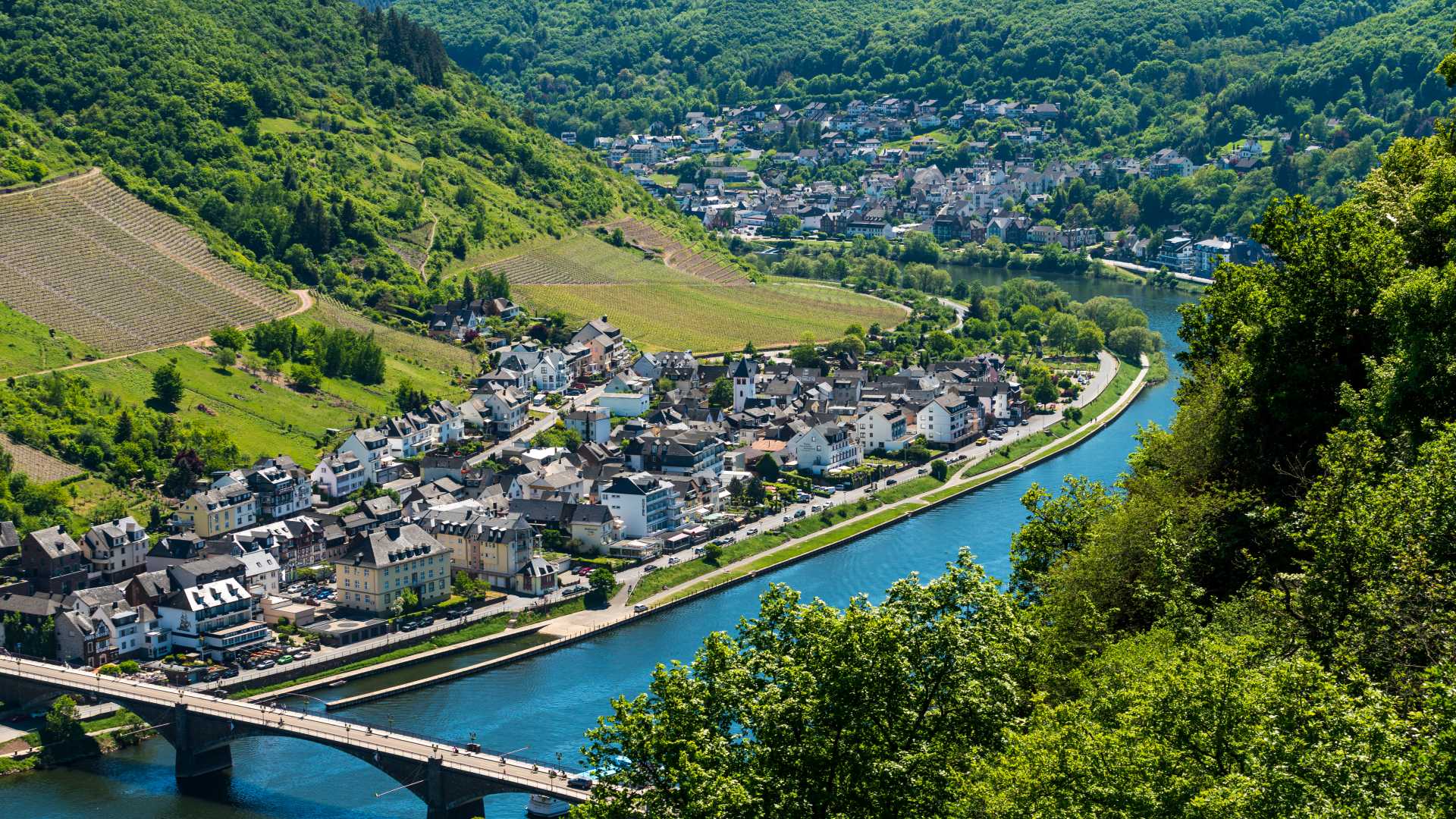Panoramic view of Cochem, a historic German town on the Moselle River, surrounded by vineyards and featuring Reichsburg Castle.