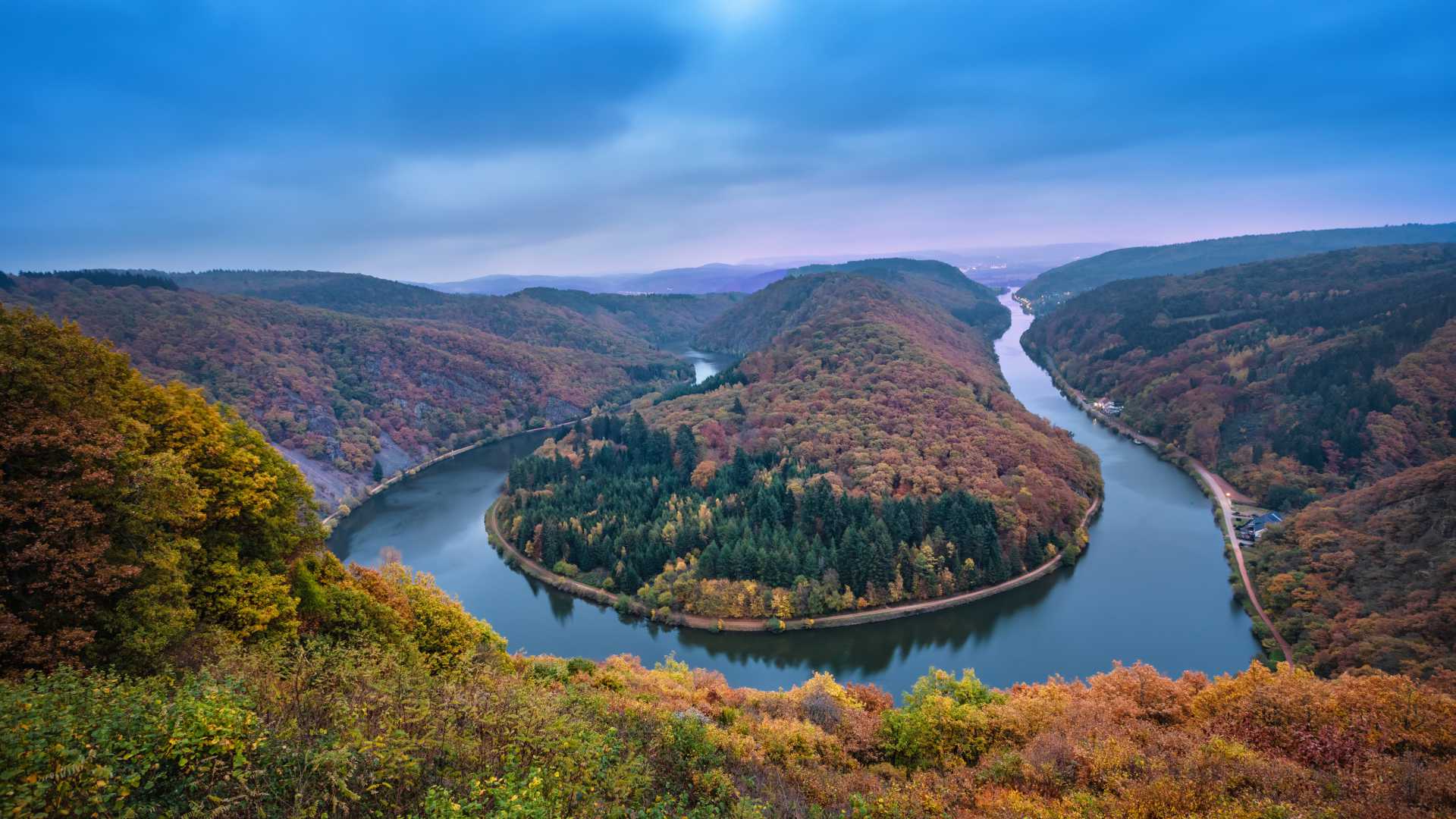 Panoramic autumnal view of the Saarschleife river bend surrounded by colorful forests in Saarland, Germany.