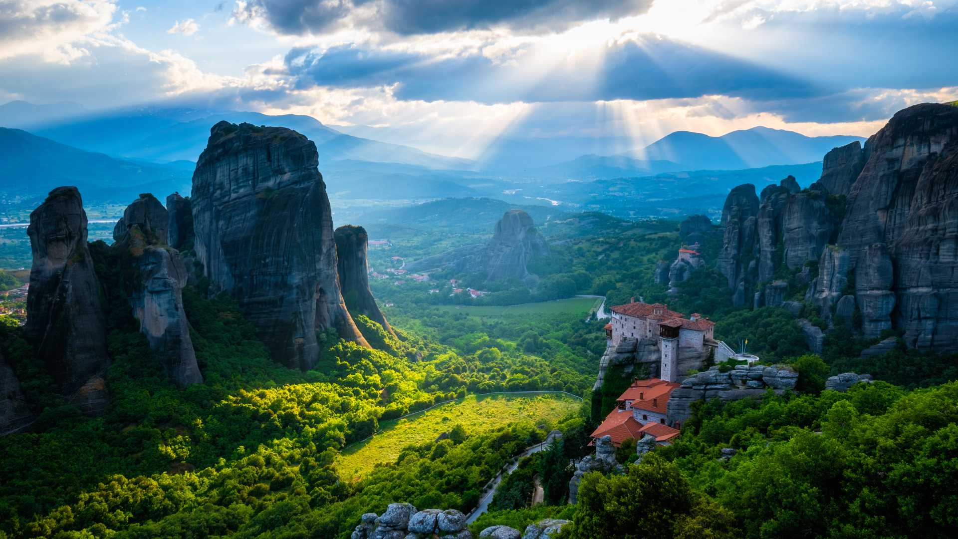 Monasteries perched on towering rock formations in Meteora, Greece, bathed in warm sunlight.