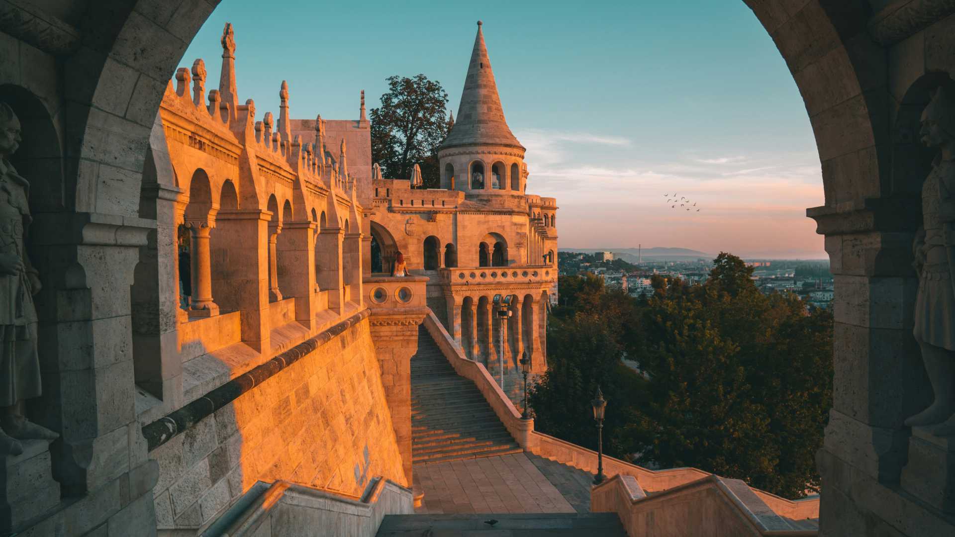 Fisherman's Bastion at sunset, Budapest, with arched walkways and city views.