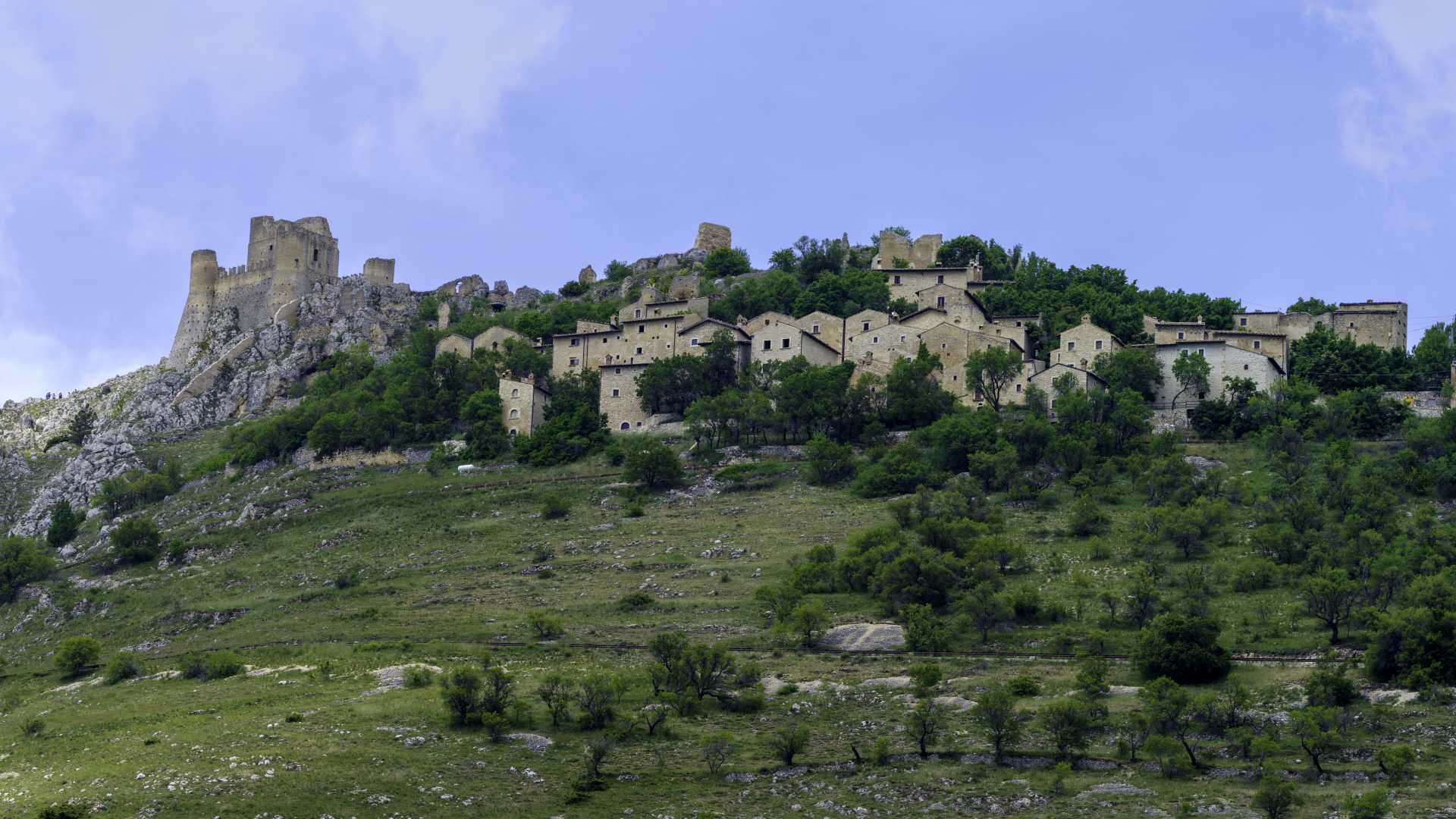 The medieval village of Calascio and Rocca Calascio nestled on a hilltop in Gran Sasso Natural Park, Abruzzo, under a clear sky.