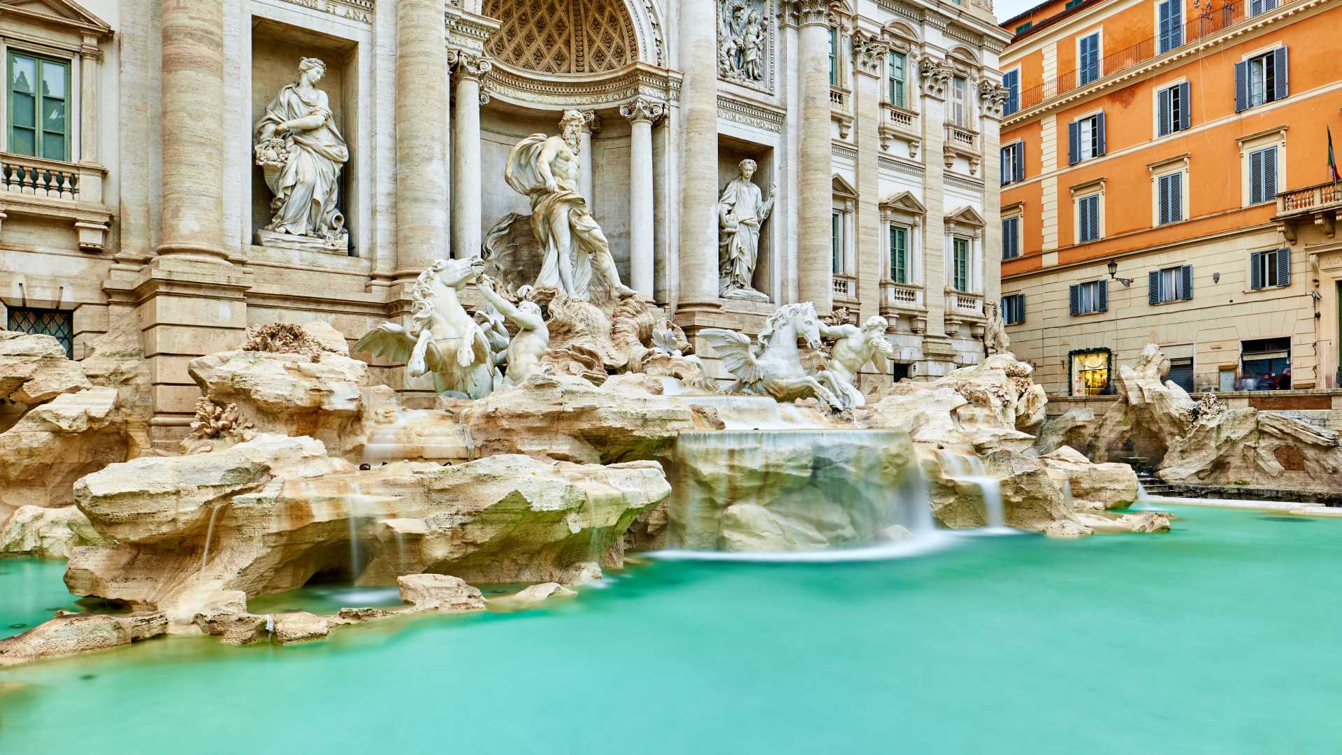 Baroque sculptures of the Trevi Fountain in Rome, Italy, with turquoise water cascading into the pool.