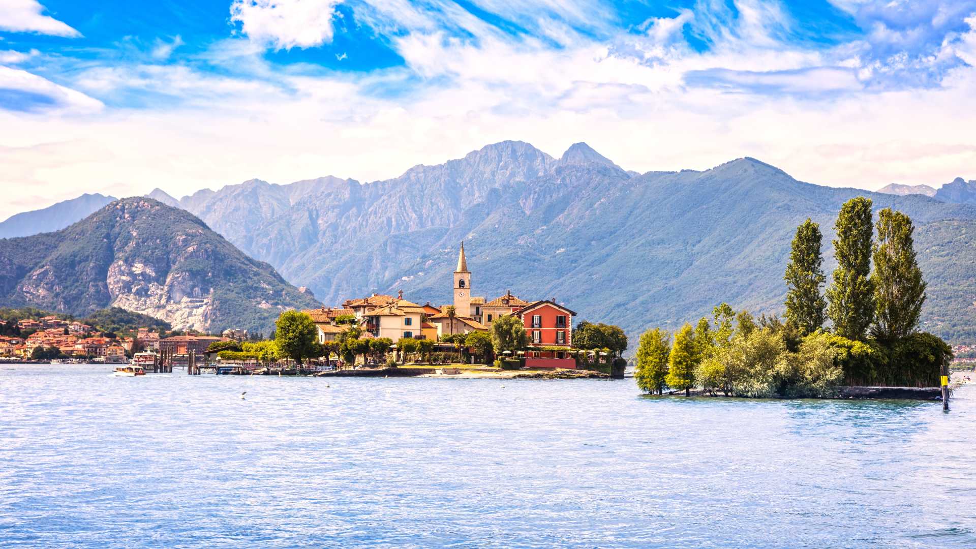 Isola dei Pescatori, a colorful village on Lake Maggiore, set against a backdrop of mountains.