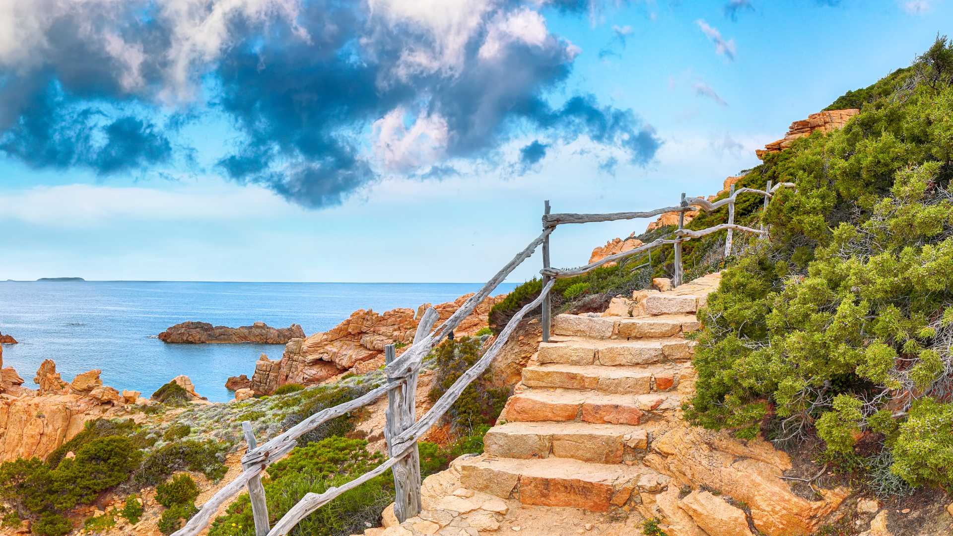 Stone steps lead up a rocky path with breathtaking views of the Mediterranean Sea in Costa Paradiso, Sardinia.