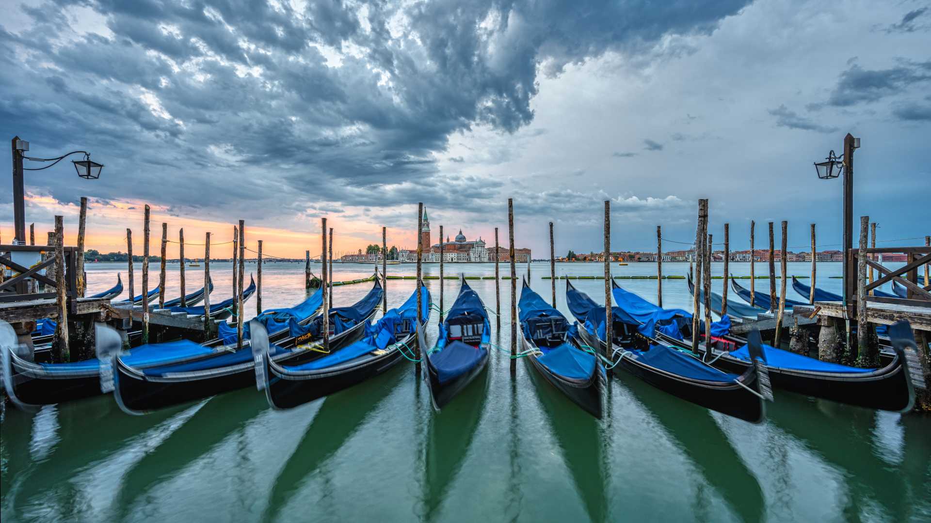 Gondolas docked at St. Mark's Square, Venice, under a dramatic sky.