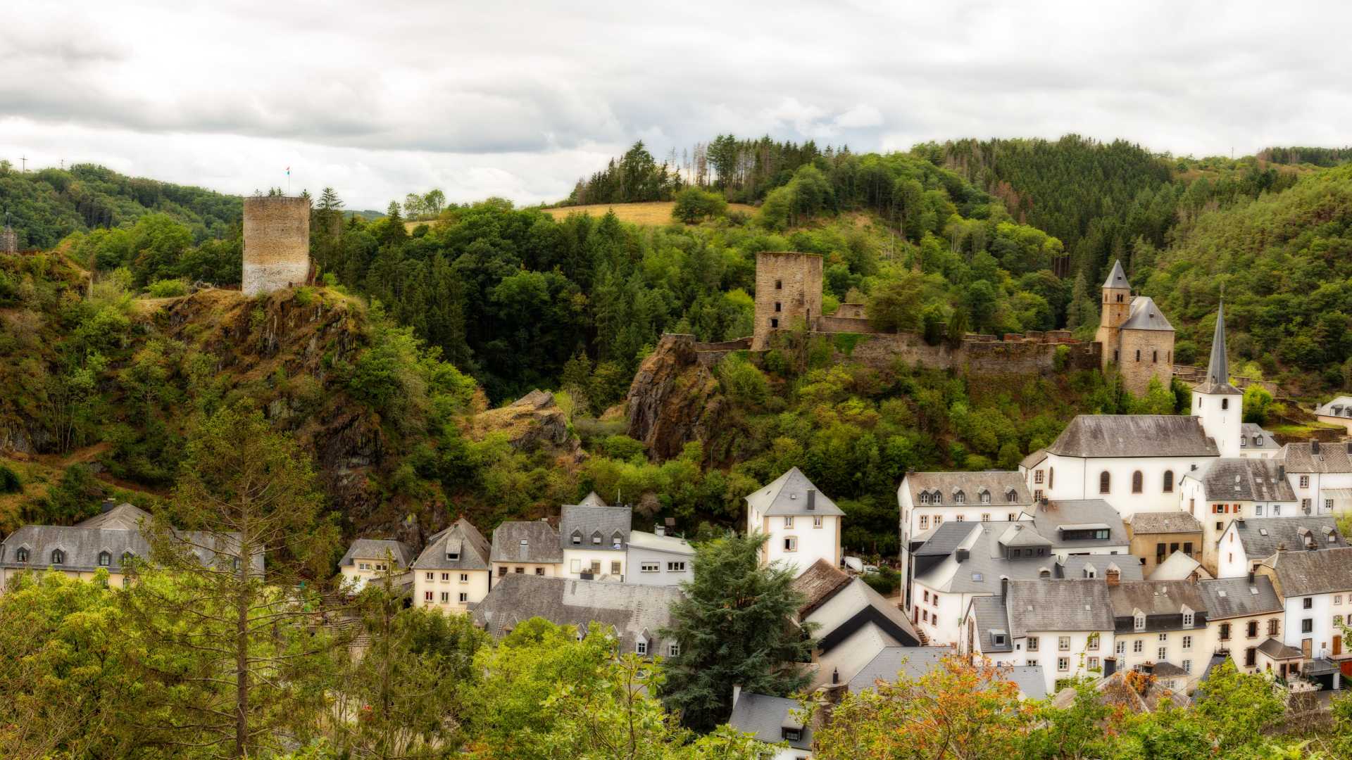 Een schilderachtig uitzicht op Esch-sur-Sûre met het kasteel en het dorp genesteld in het groene landschap.