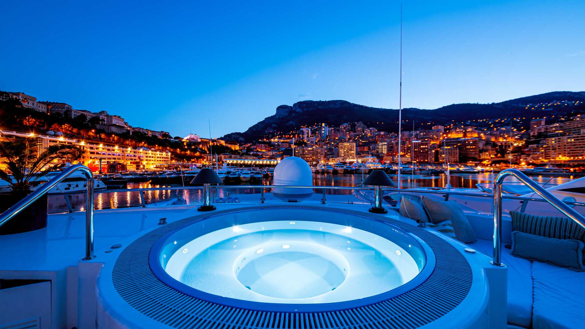 Yachtpool in Monaco mit atemberaubendem Blick auf die beleuchtete Skyline und den Hafen bei Nacht.