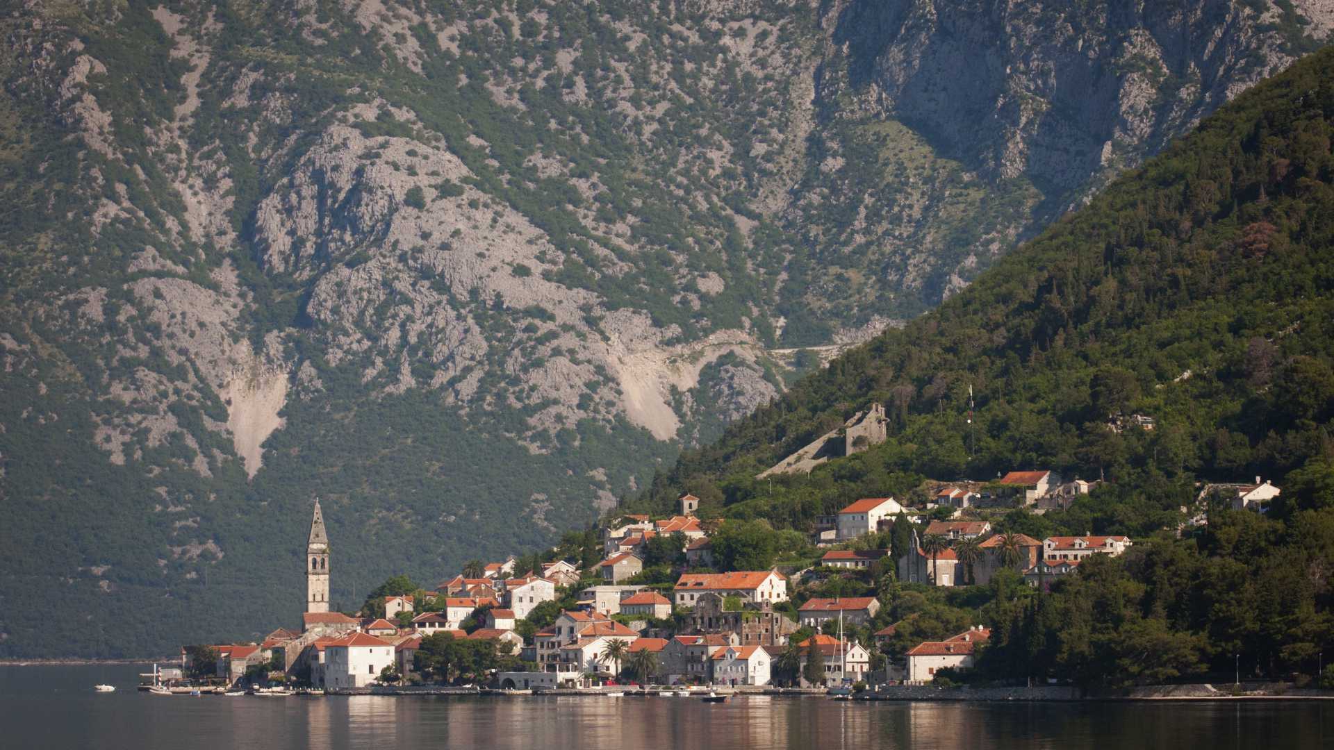 Charmant village de Perast avec des maisons aux toits rouges nichées à flanc de montagne, reflété dans la paisible baie de Kotor, au Monténégro.