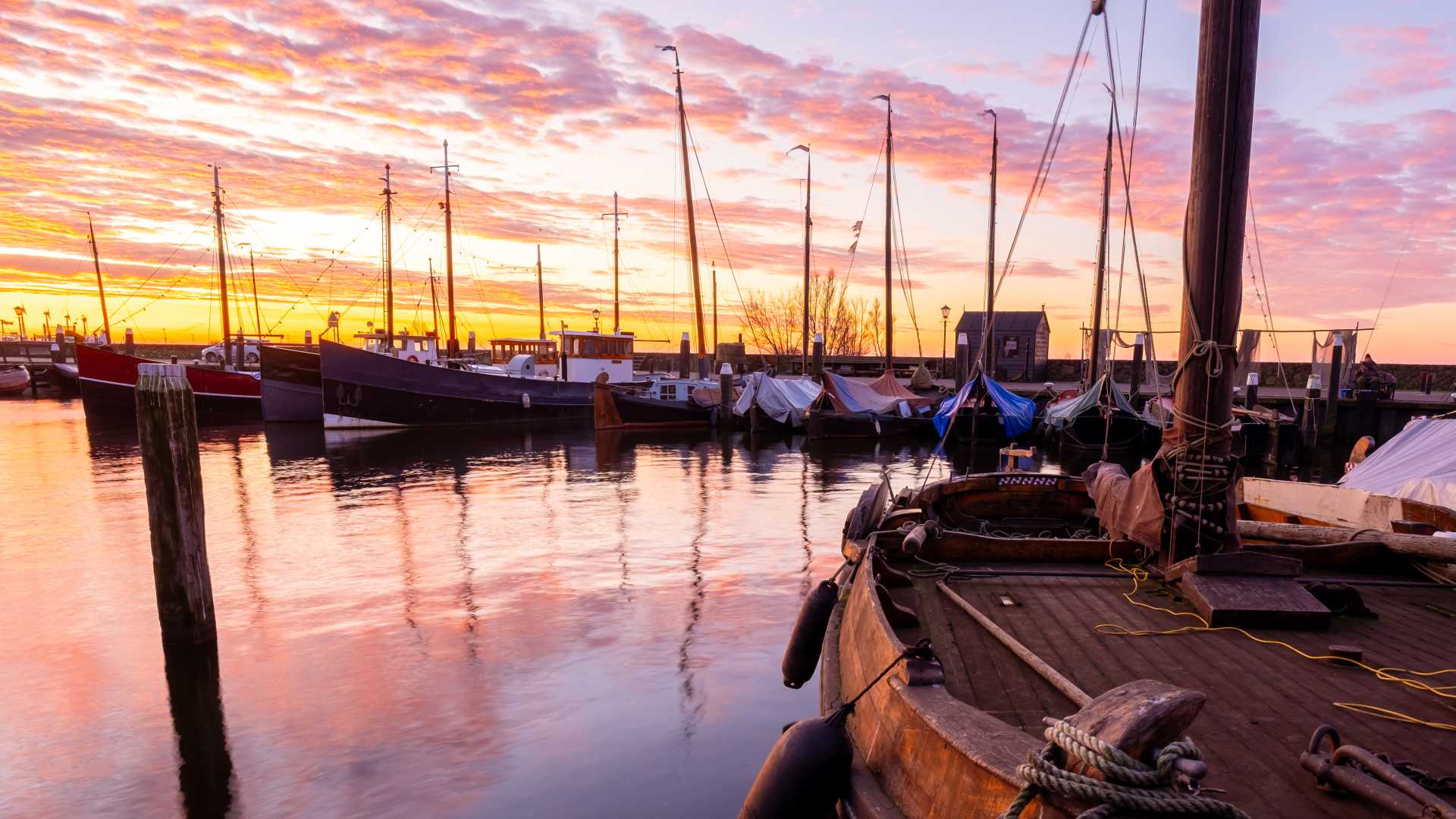 Vissersboten afgemeerd in de historische haven van Urk, badend in een glorieuze zonsondergang.