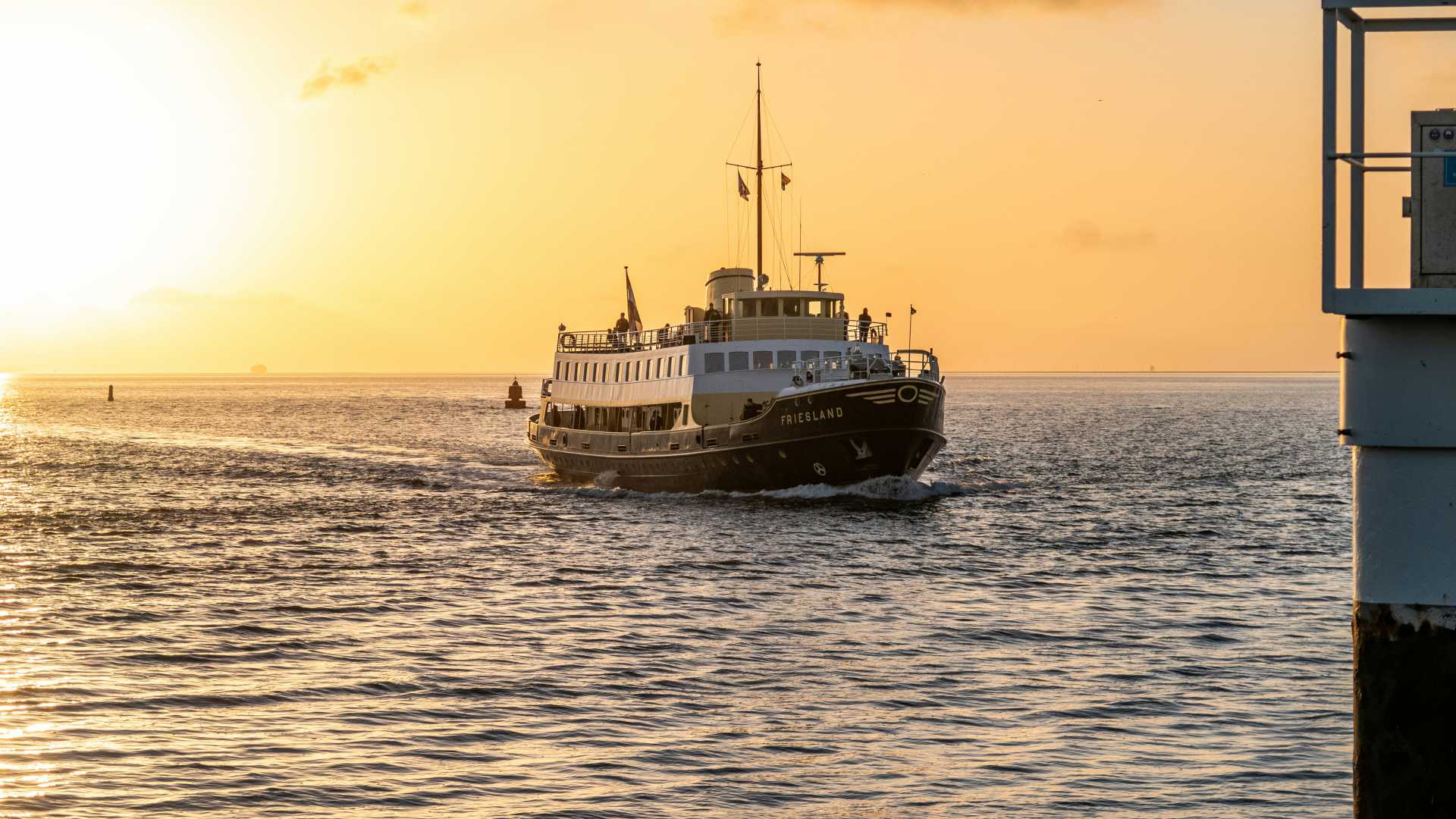 The ferry 'Friesland' sails toward the port of Harlingen as the sun sets.