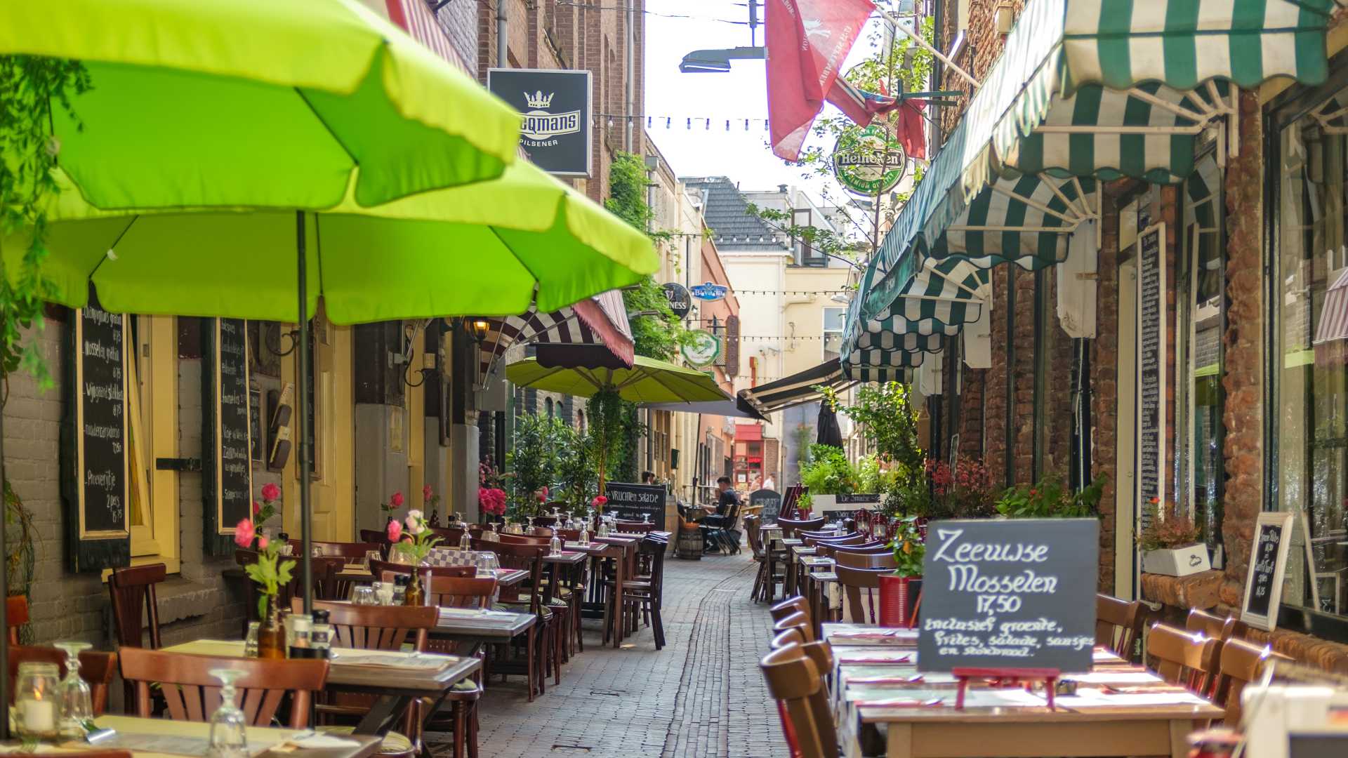 Charmante straat met restaurants in Arnhem met kleurrijke parasols en uitnodigende zitplaatsen buiten.