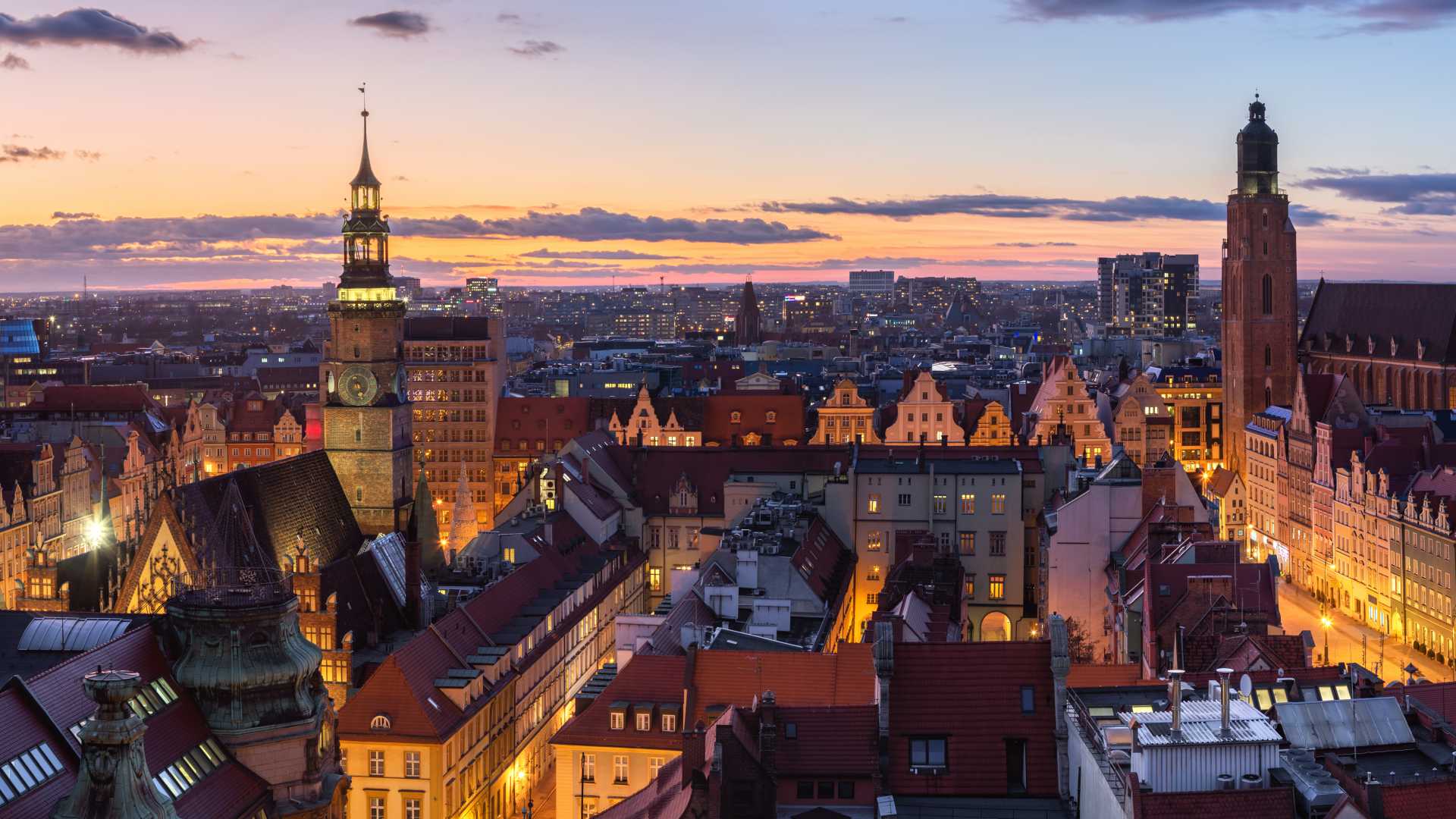 Luchtfoto van Wrocław in de schemering, met verlichte historische gebouwen en kerktorens.