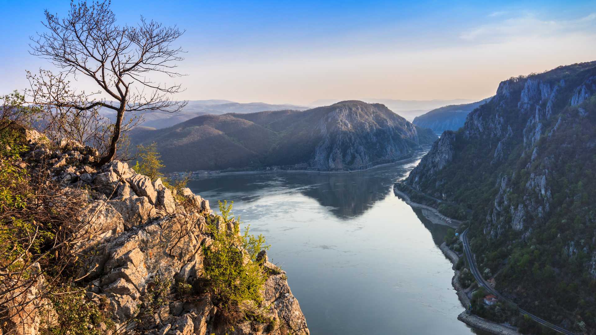 Een panoramisch uitzicht op de Donaukloof met ruige kliffen en de rivier de Donau die de lucht weerspiegelt.