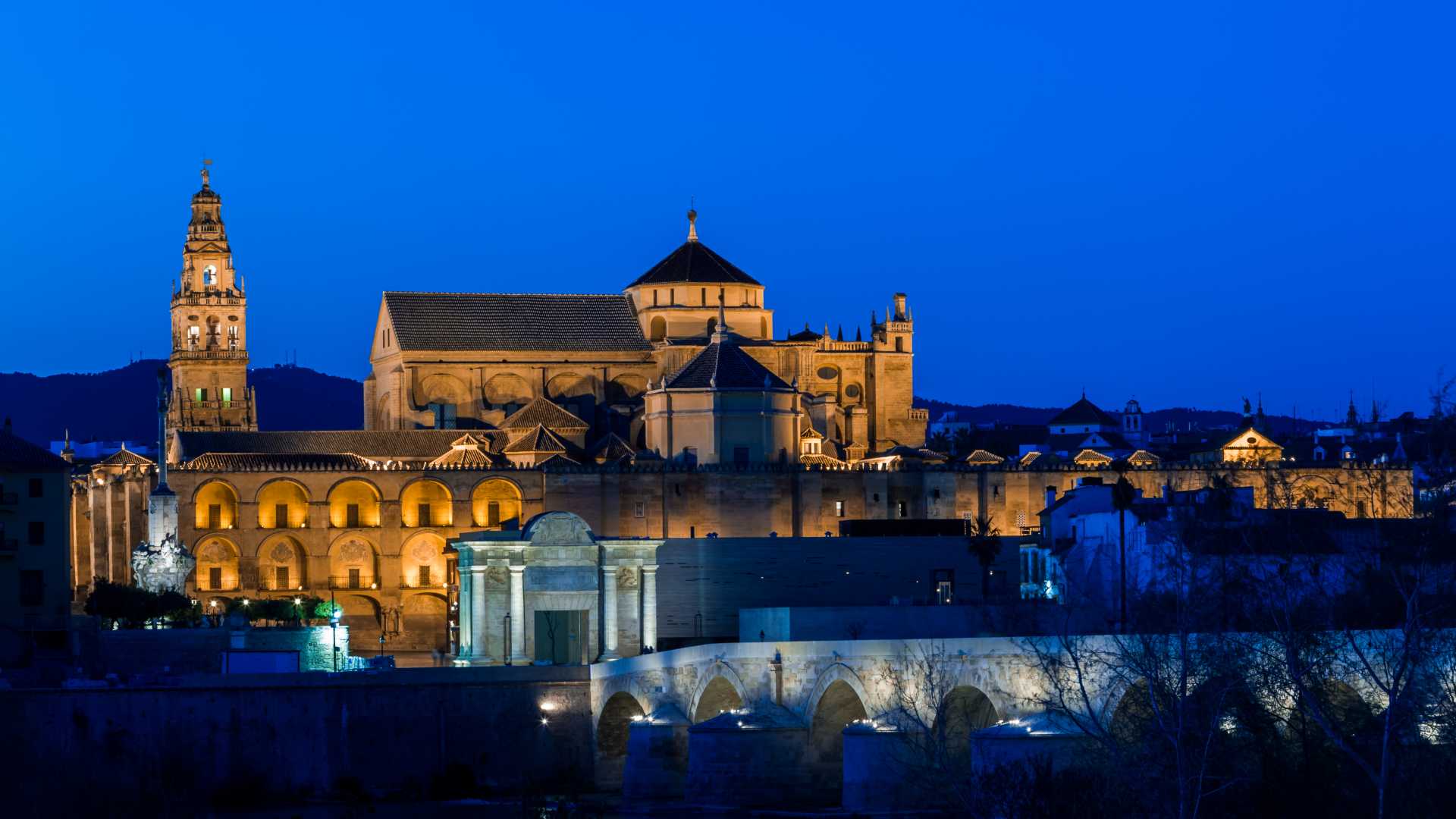 De Mezquita-kathedraal en de Romeinse brug in Córdoba, badend in het zachte schijnsel van de schemering.