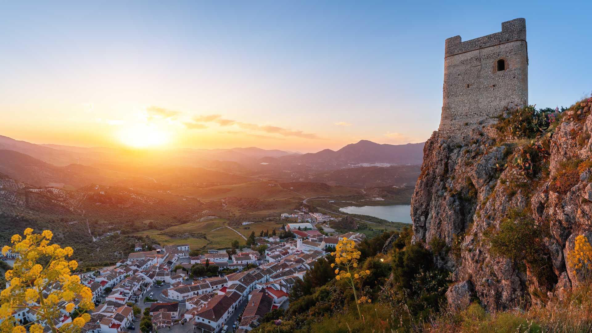 Castillo de Zahara de la Sierra al atardecer, con vistas al pueblo y a las montañas circundantes.