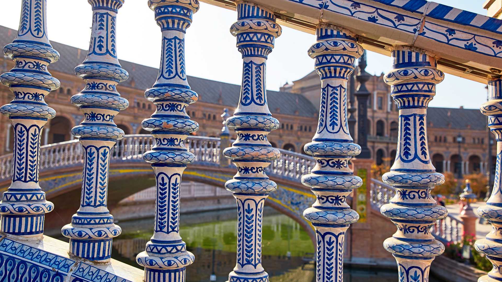 Versierde blauw-witte keramische balusters omlijsten een uitzicht op de bruggen en het centrale gebouw op Plaza de España in Sevilla, Spanje.
