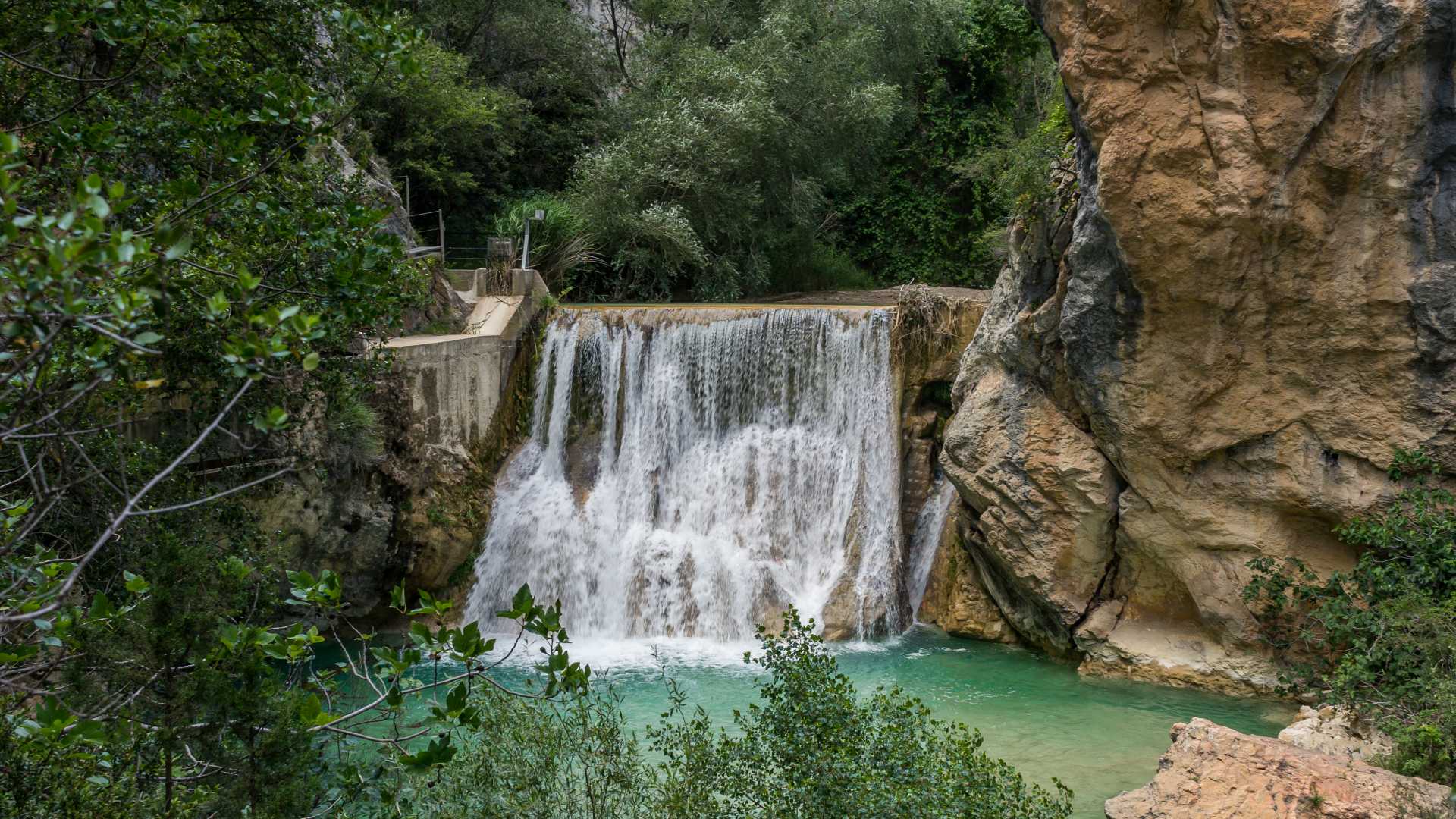 Een pittoreske waterval stroomt in een heldere poel, omgeven door het dramatische canyonlandschap van Alquézar, Spanje.