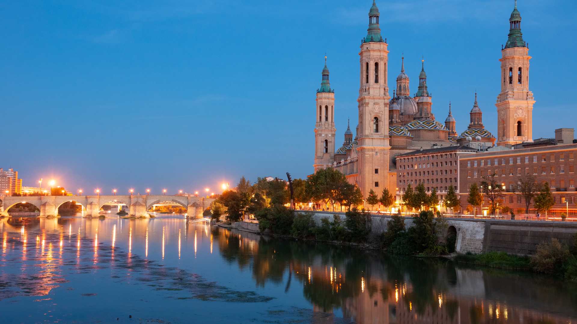 De Basiliek van Onze-Lieve-Vrouw van de Pilaar verlicht in de schemering, weerspiegeld in de Ebro in Zaragoza, Spanje.