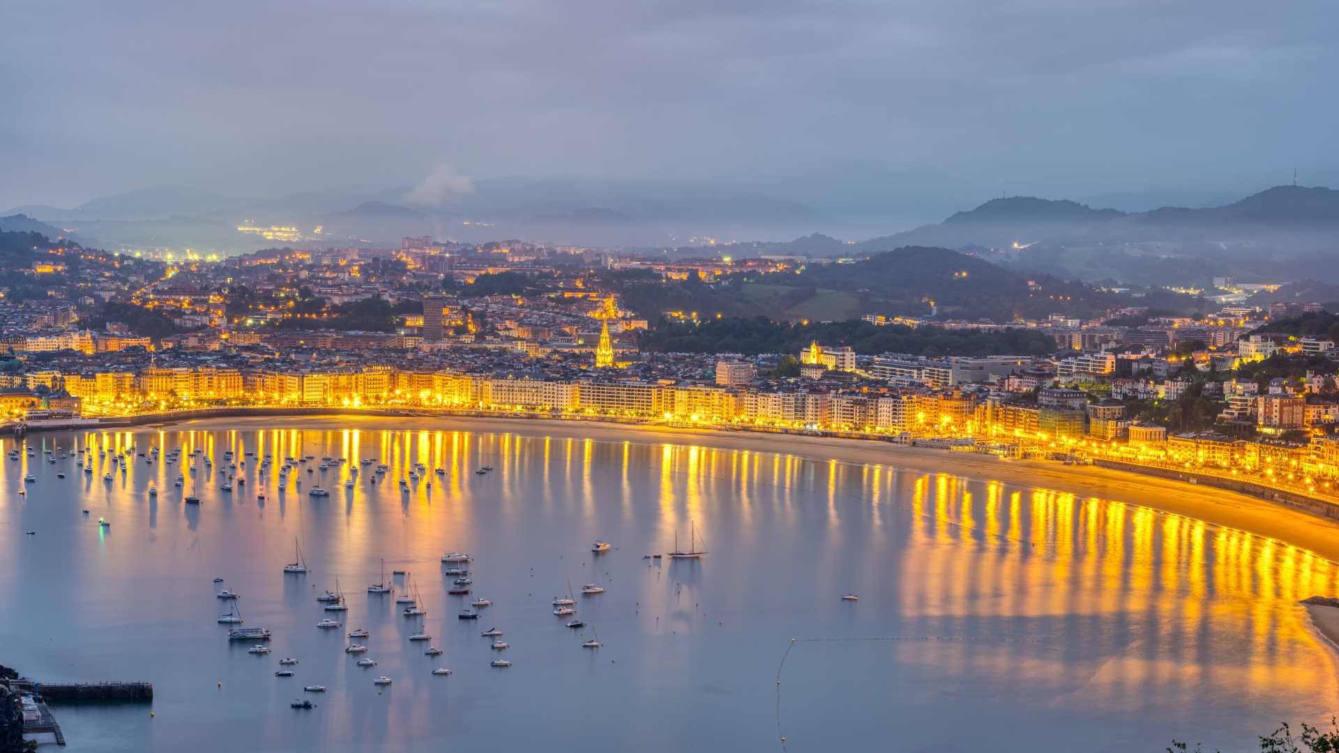 La Concha strand in San Sebastian bij zonsopgang, stadslichten ontmoeten de zonsopgang.